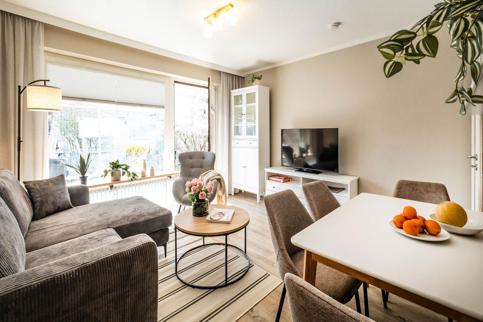 Wohn- und Essbereich mit Sofa, Esstisch und Fernseher.