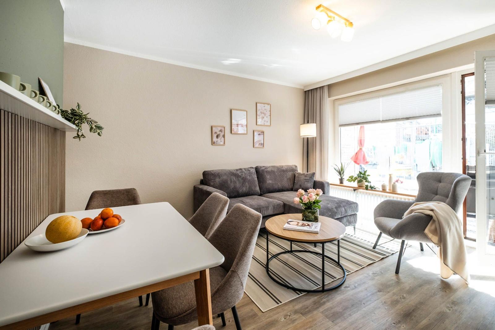 Wohn- und Essbereich mit Sofa, Esstisch und Fenster. Auf dem Tisch Obst.