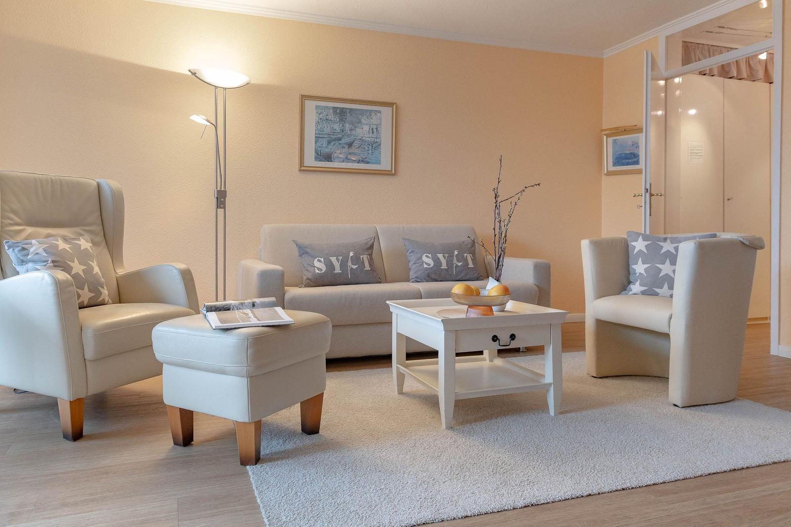 Wohnzimmer mit Sofa, zwei Sesseln, Couchtisch und Teppich.