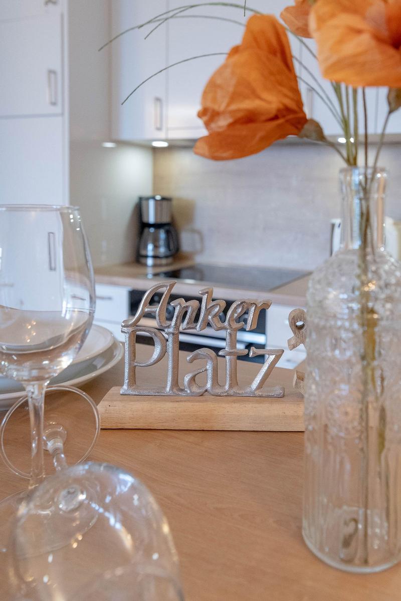 Tisch mit Gläsern, Blumen und Schild Anker Platz in Küche.
