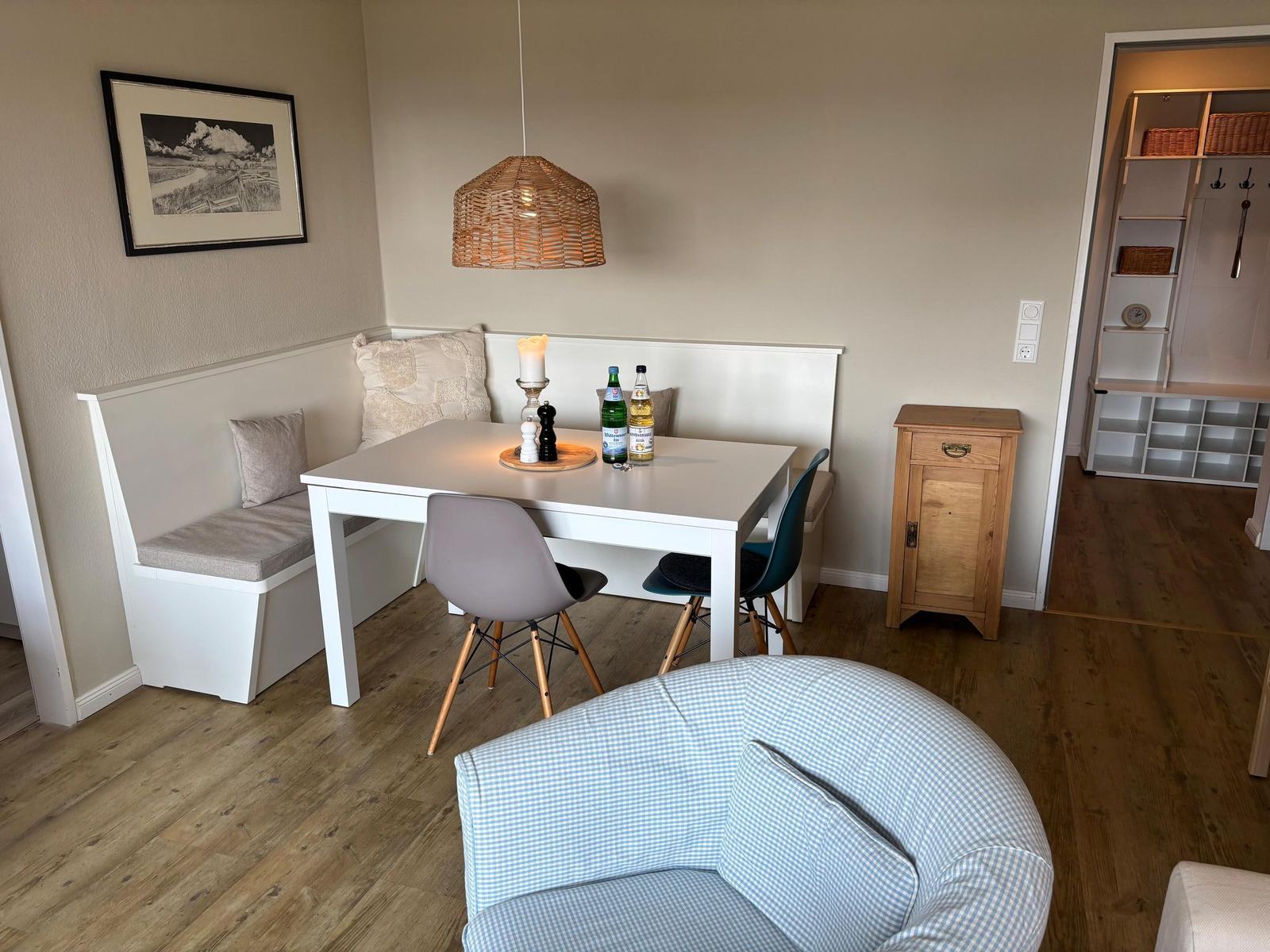 Essbereich mit Tisch, Stühlen und Sitzbank. Hängelampe und Holzfußboden.