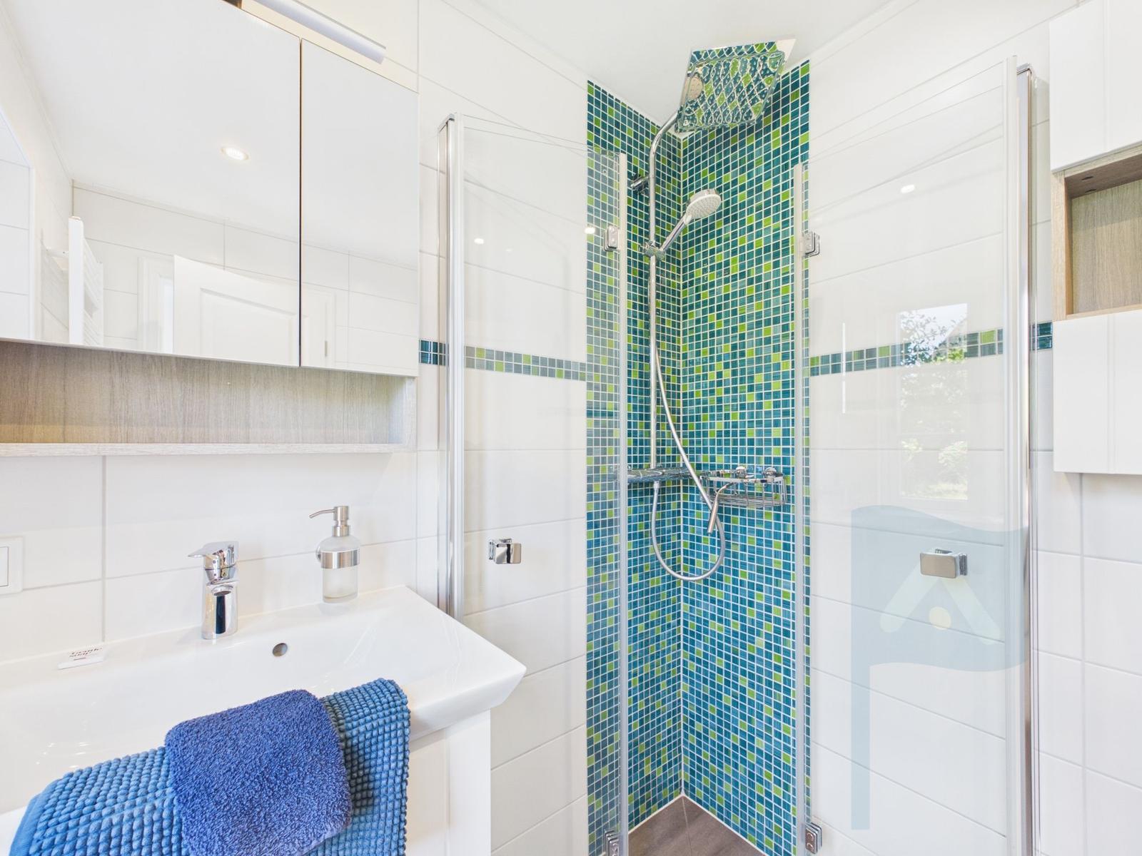 Badezimmer mit Dusche, Waschbecken und Spiegel