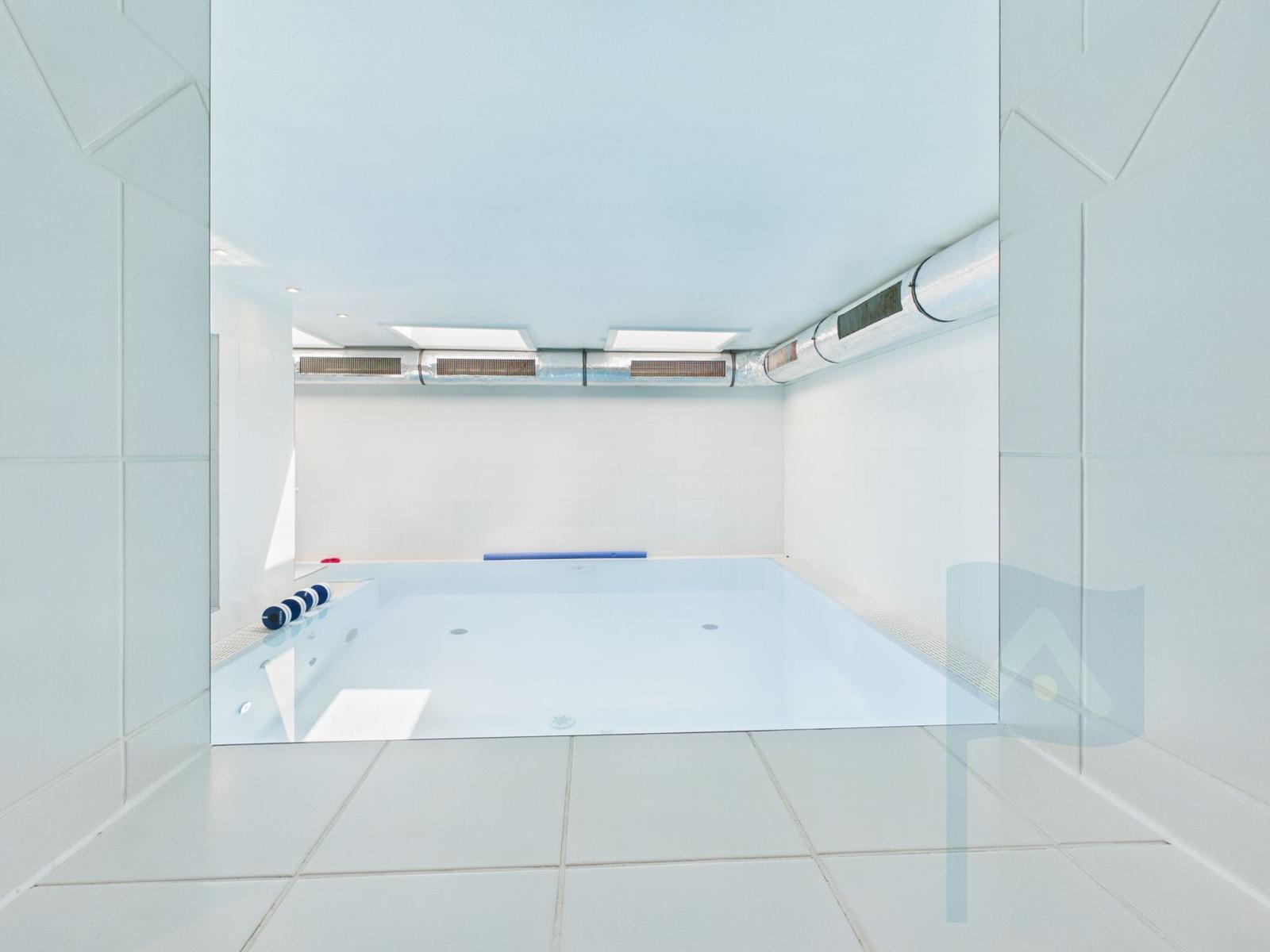 Indoor pool with white tiles and ceiling ventilation system