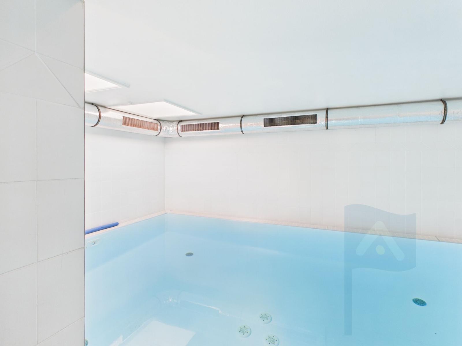 Indoor pool with white walls and ceiling vents.