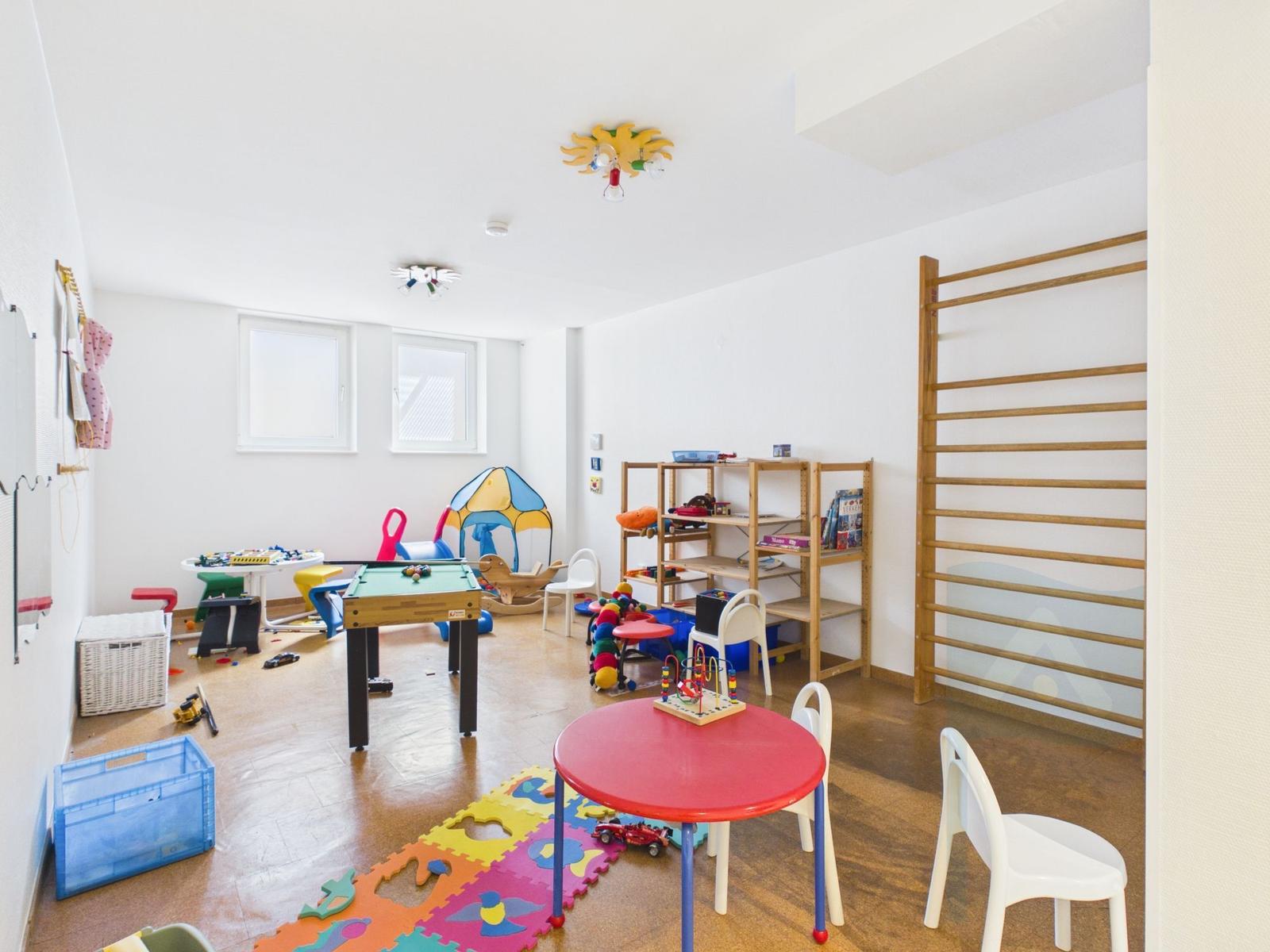 Childrens room with toys, tables, chairs, and gymnastic equipment.