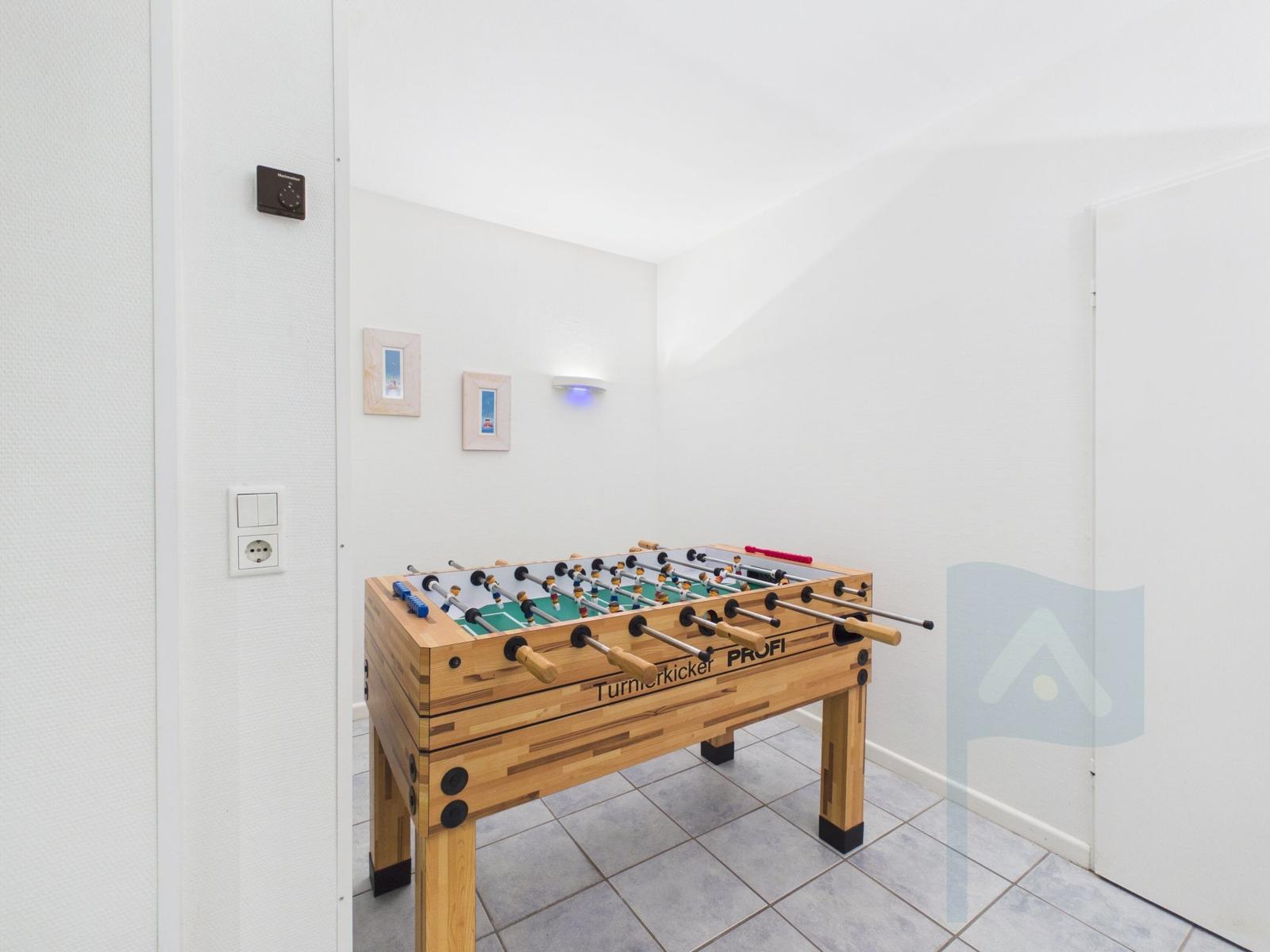 A foosball table is in a room with white walls and tiled floor.