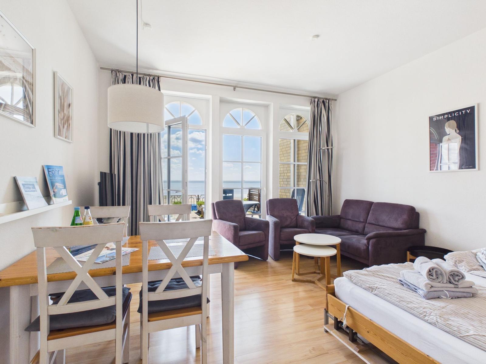 Apartment with dining area, sofa, armchairs, and sea view.