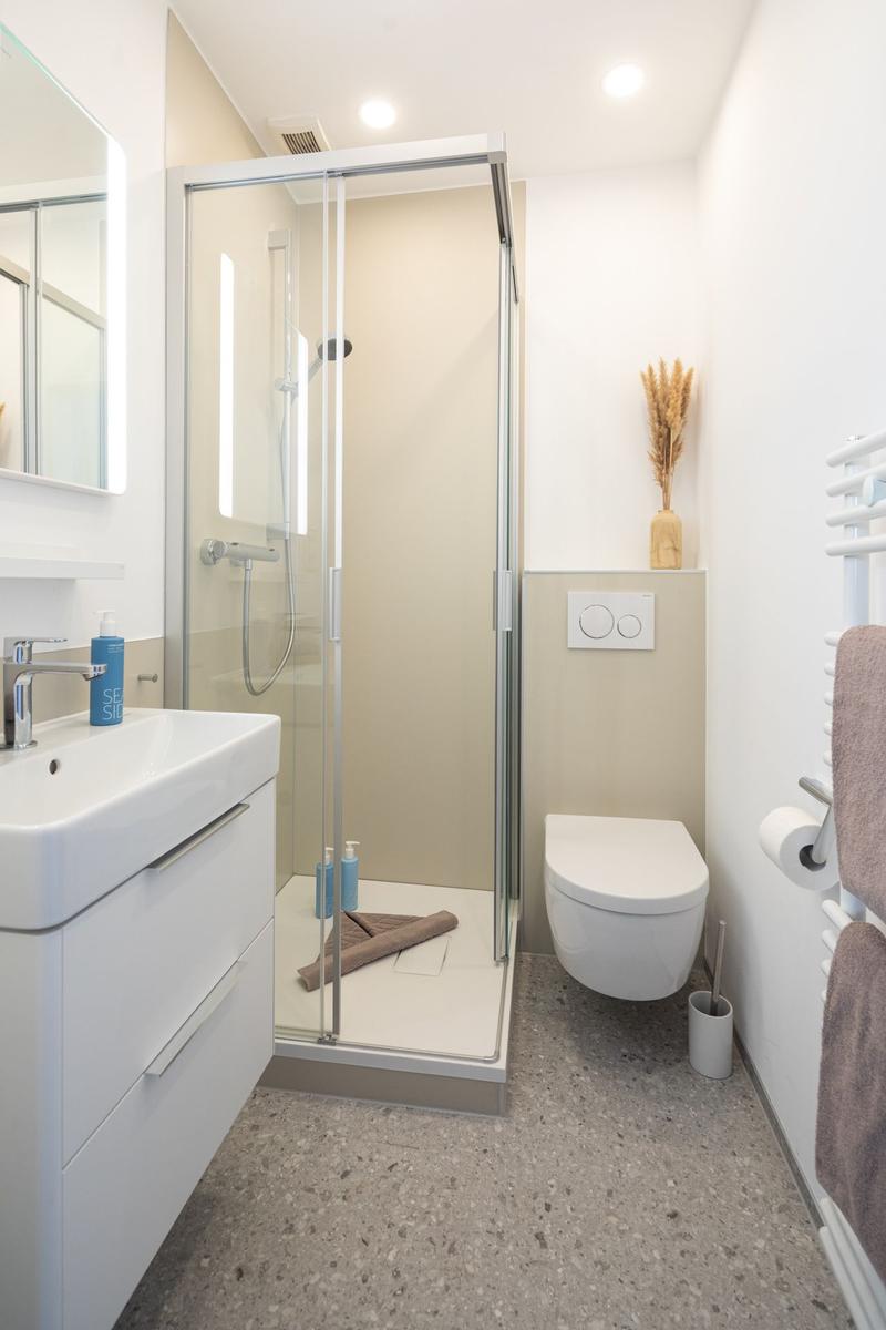 Dusche mit Glaswand, Waschbecken und Toilette in moderner Badezimmerausstattung.
