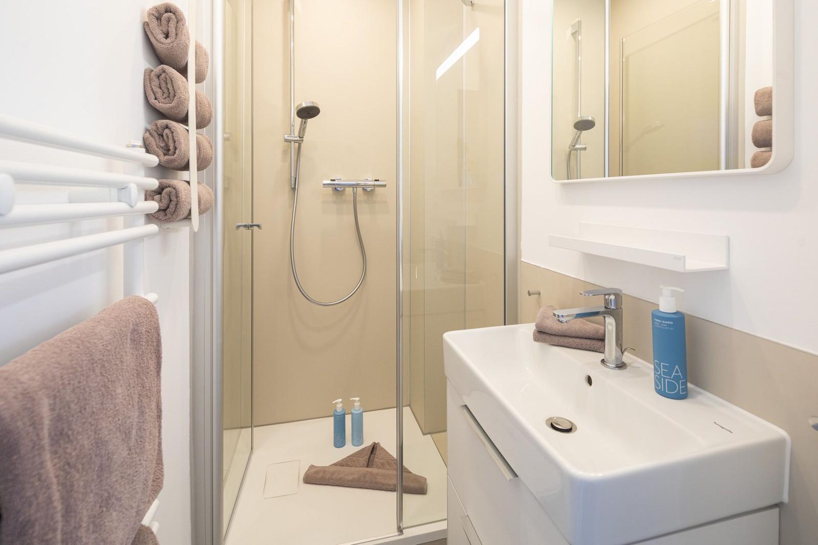 Badezimmer mit Dusche, Waschbecken und Handtuchhalter.