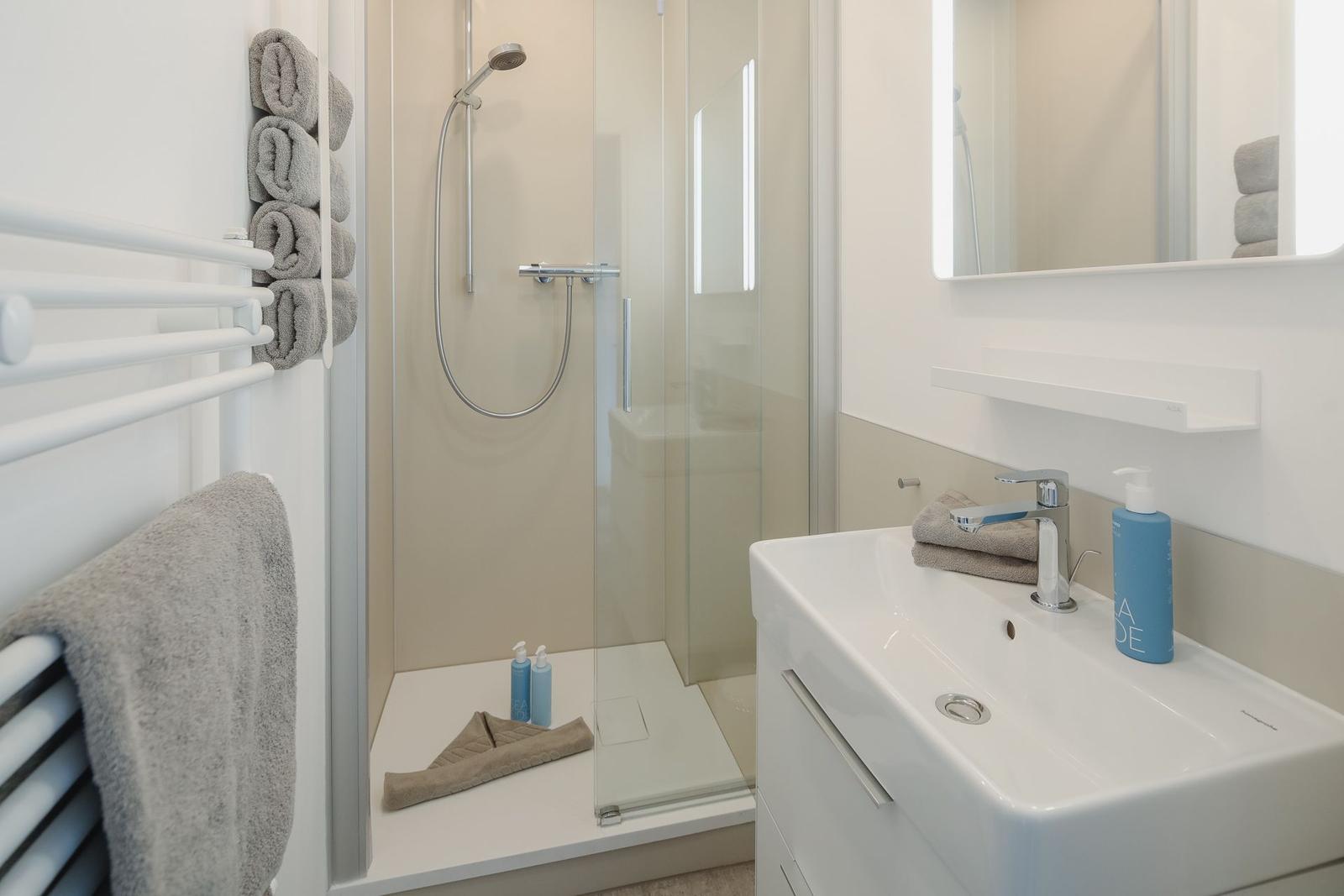 Bathroom with shower, sink, and towels.