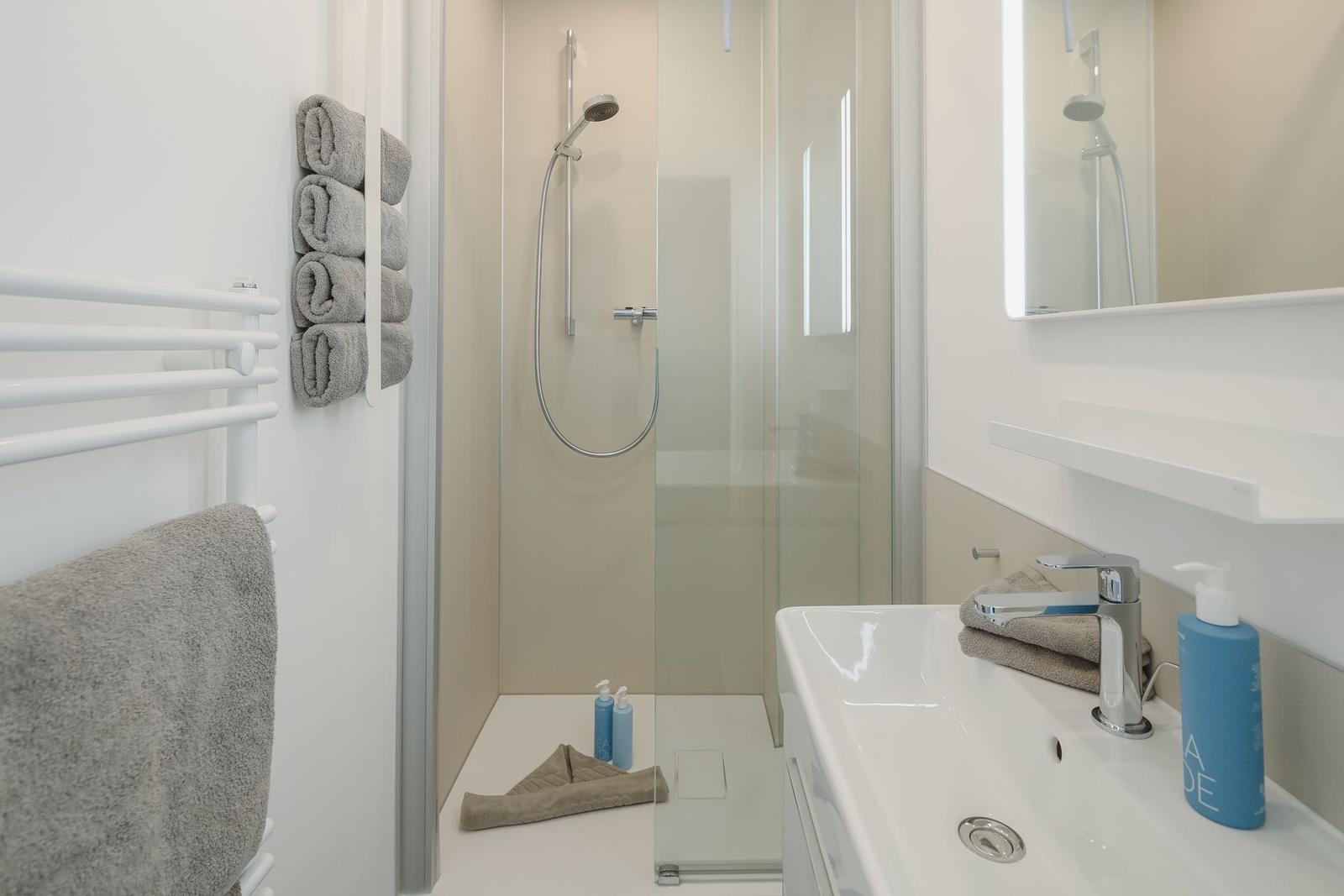 Bathroom with shower, sink, and towels.