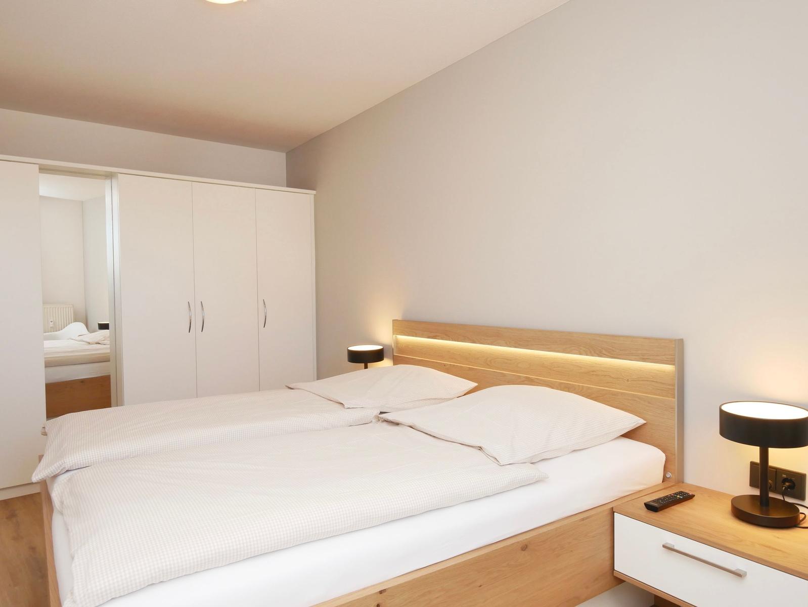 Schlafzimmer mit Doppelbett, Nachttisch und Kleiderschrank.