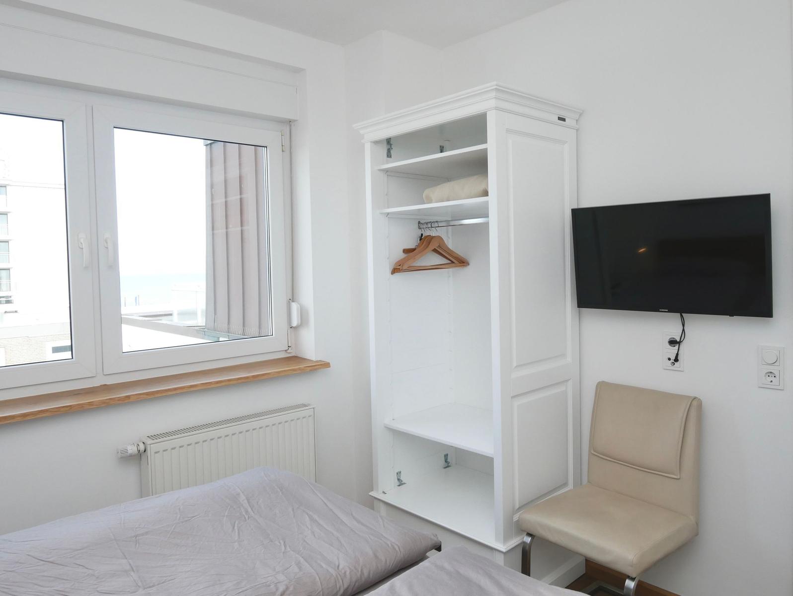 Zimmer mit Bett, Kleiderschrank, TV und Fenster mit Blick.