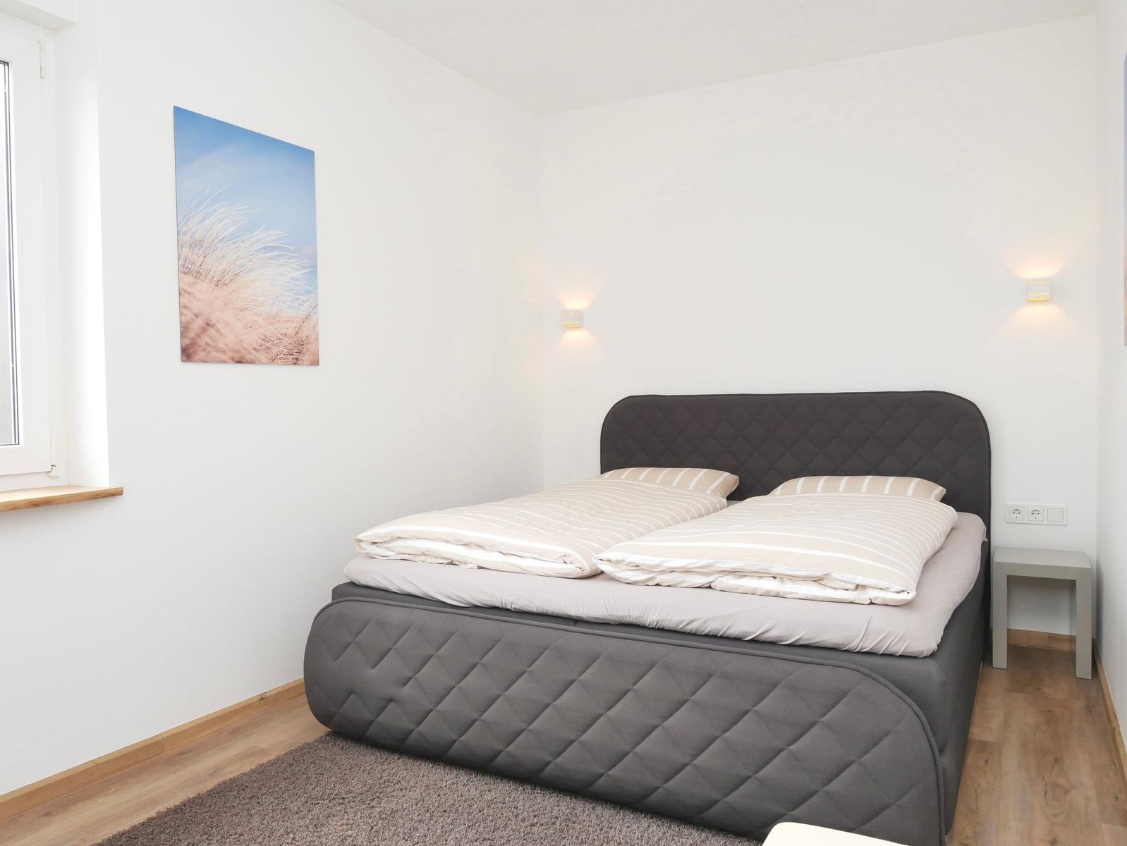 Schlafzimmer mit Doppelbett, Wandbild und Nachttisch.