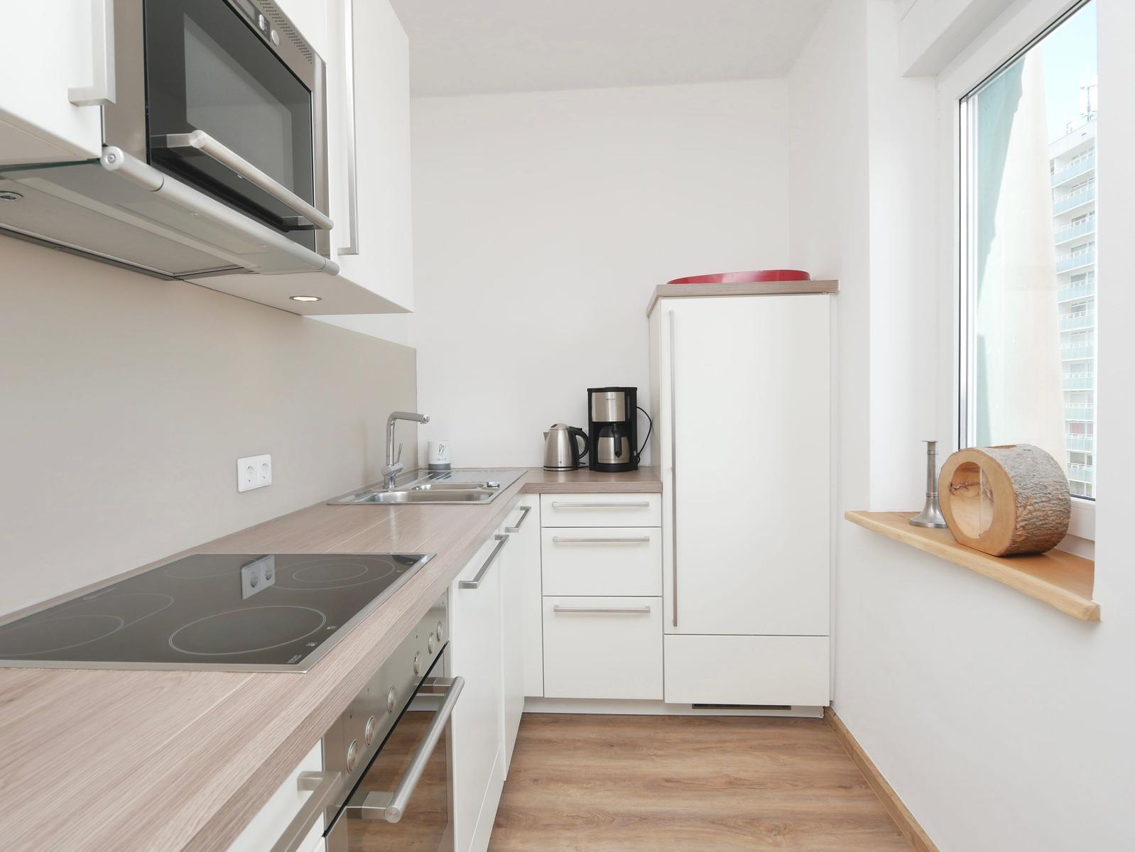 Küche mit Dunstabzug, Spüle, Herd, Kühlschrank und Fensterbank.