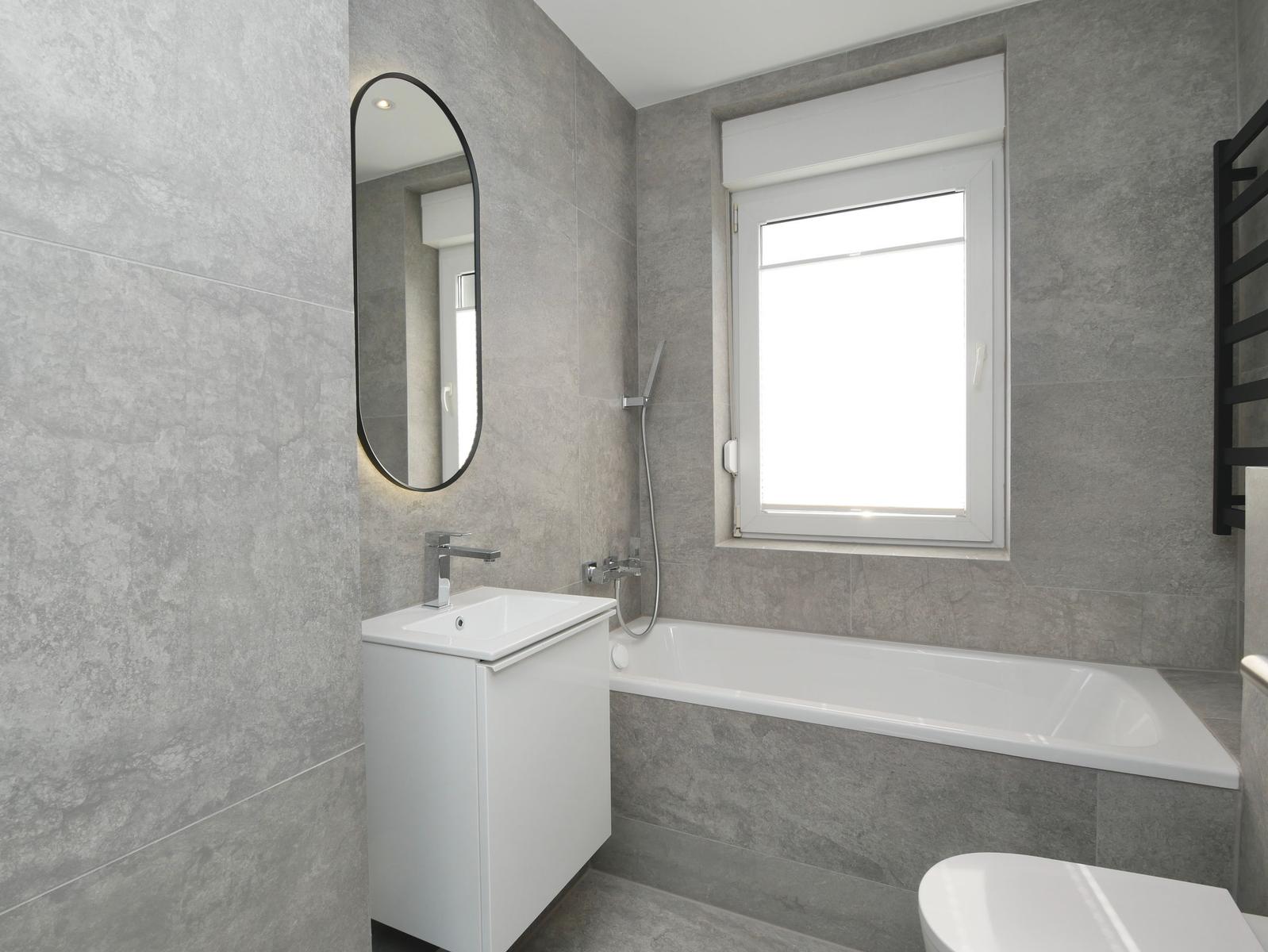 Badezimmer mit Badewanne, Waschbecken und Fenster.