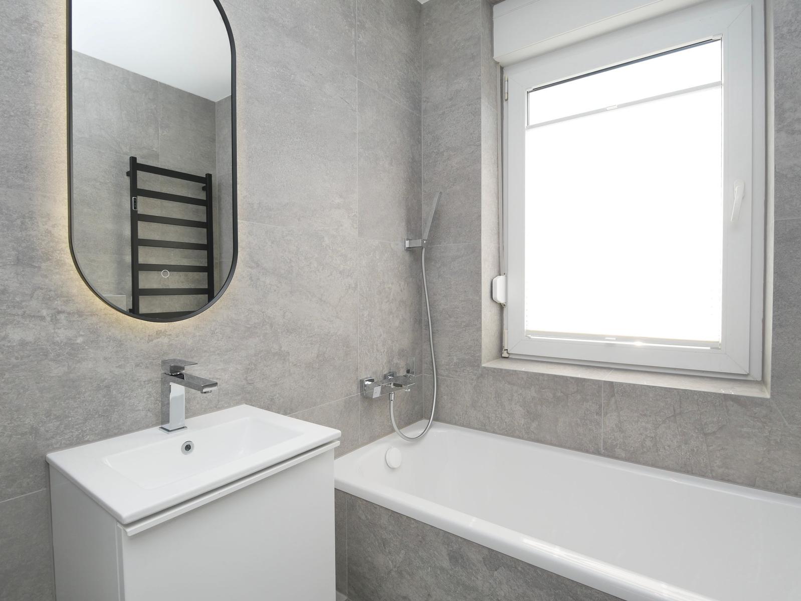 Badezimmer mit Badewanne, Spiegelschrank und Fenster