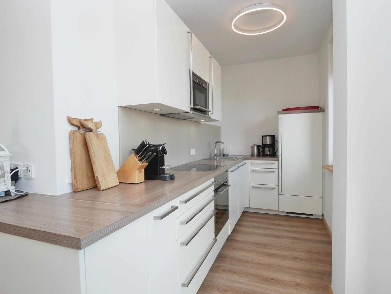 Moderne Küche mit Arbeitsplatte, Kühlschrank und Kochfeld.