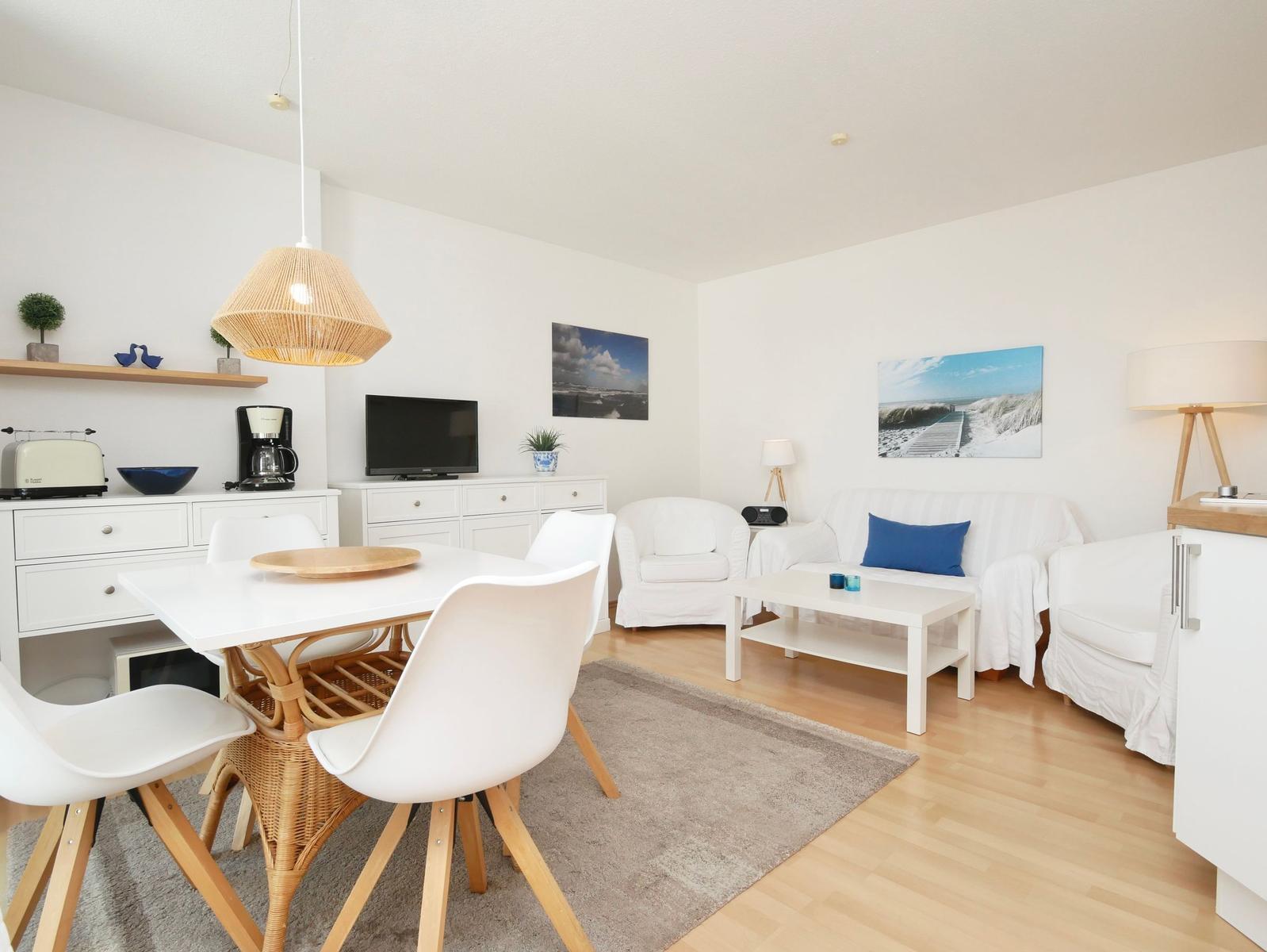Wohn- und Essbereich mit weißem Sofa, Esstisch und Küchenzeile.