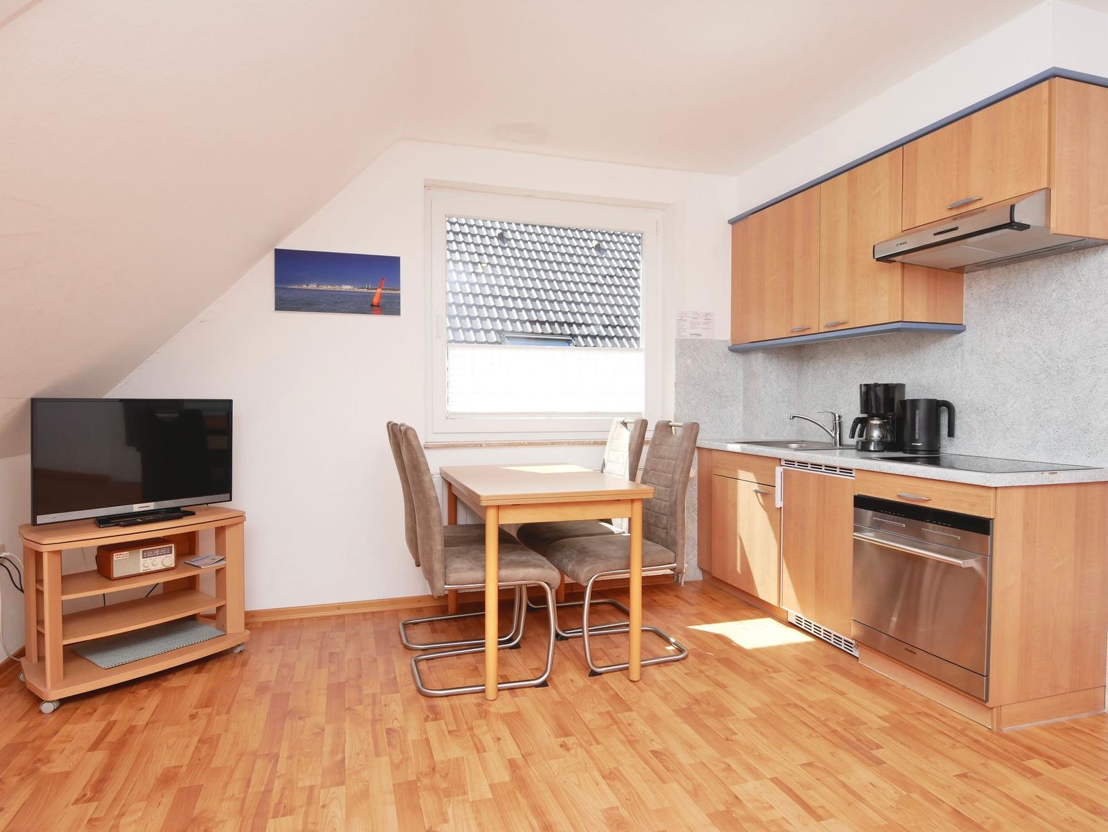 Küche mit Essbereich, Fernseher und Holzboden. Fenster mit Dachziegelblick.