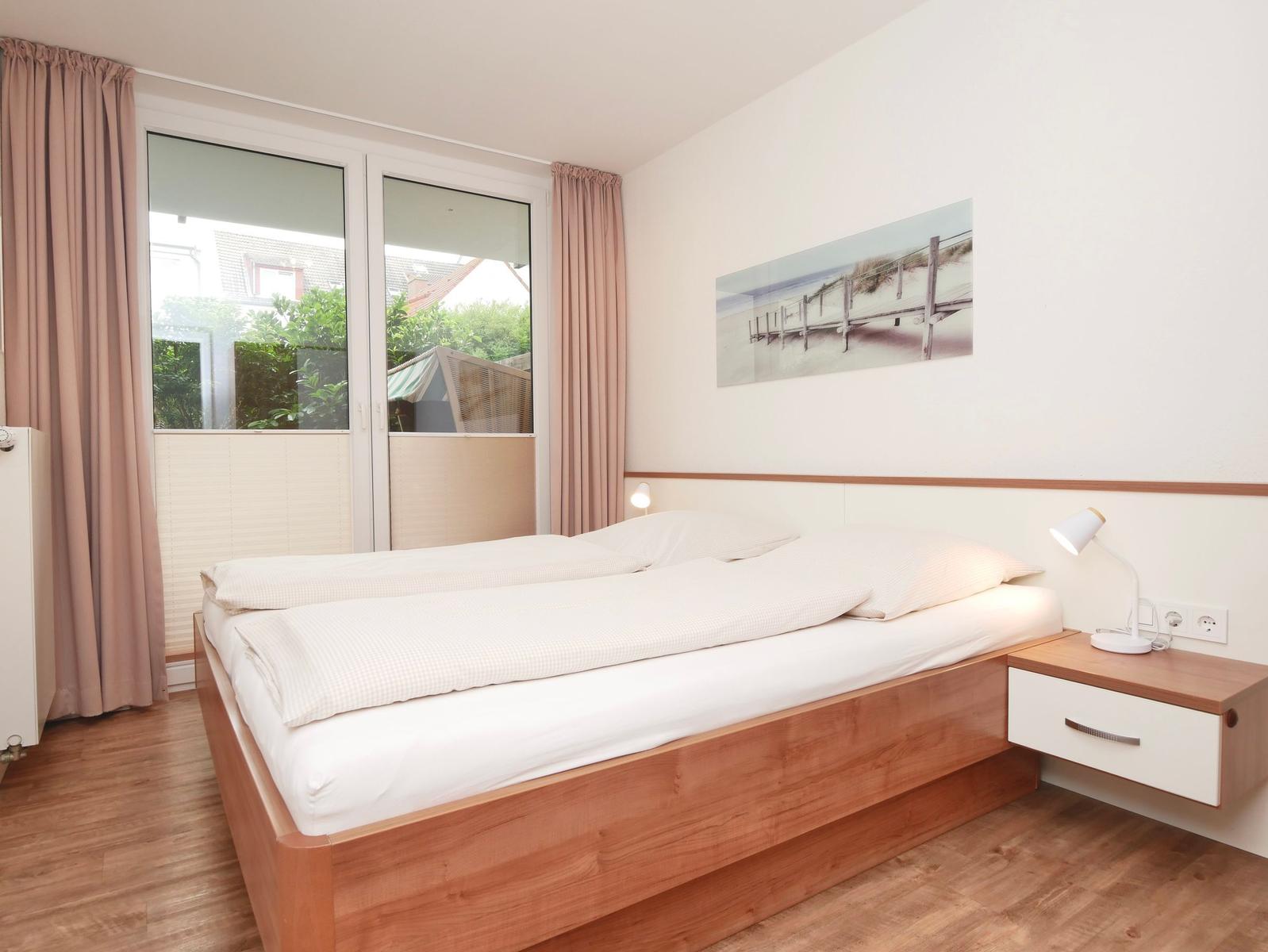 Schlafzimmer mit Doppelbett, Fenster und Wandbild.