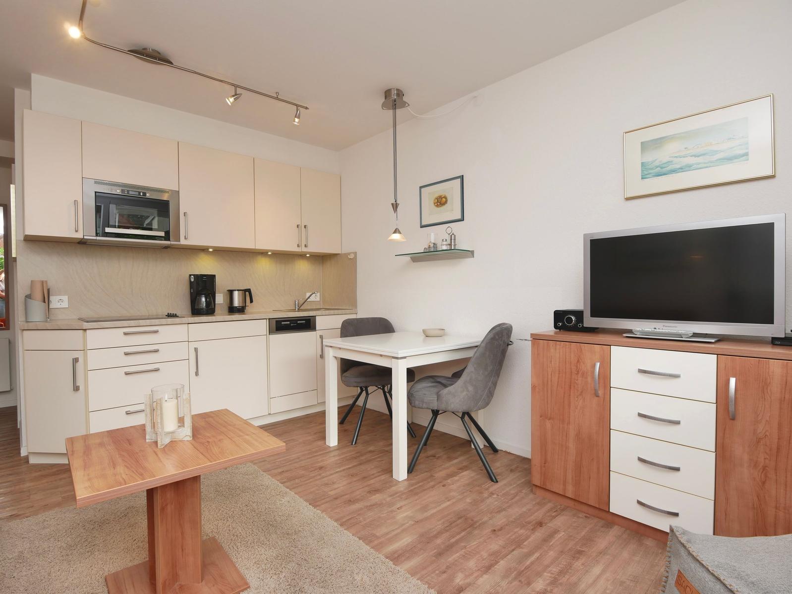 Küche mit Essbereich und Wohnbereich mit Fernseher und Schrank.