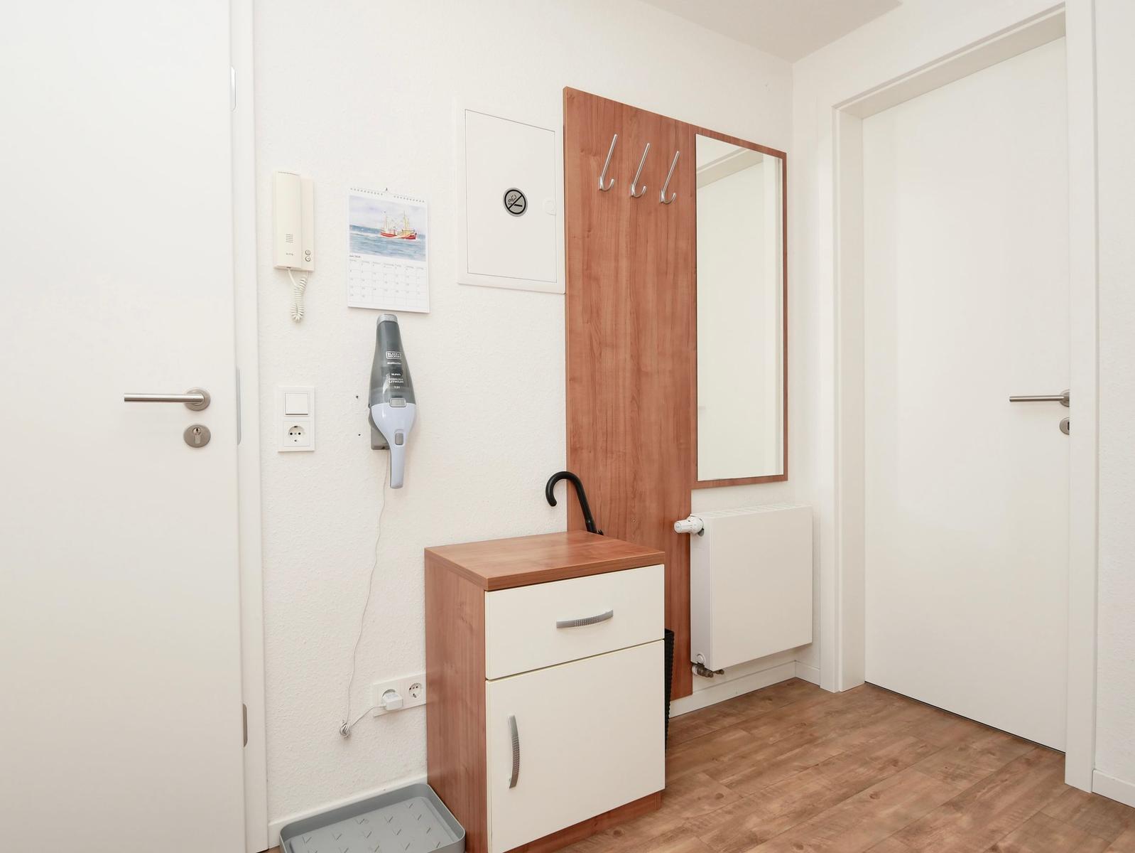 Eingangsbereich mit Kleiderschrank, Spiegel und Haartrockner an der Wand.