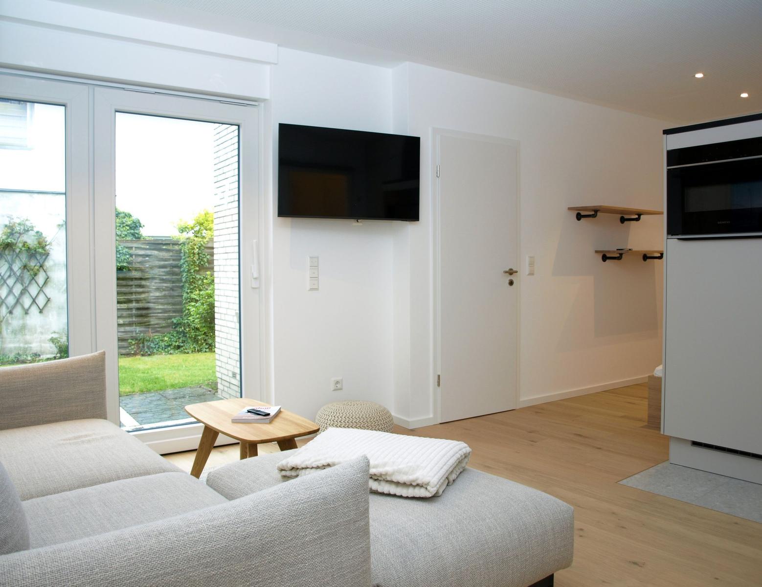 Wohnbereich mit Sofa, TV und Blick auf den Garten.