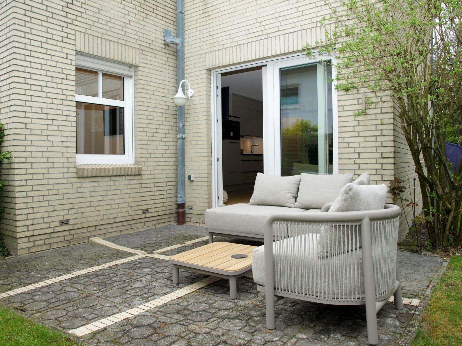 Terrasse mit Sitzgruppe und Blick in die Küche.