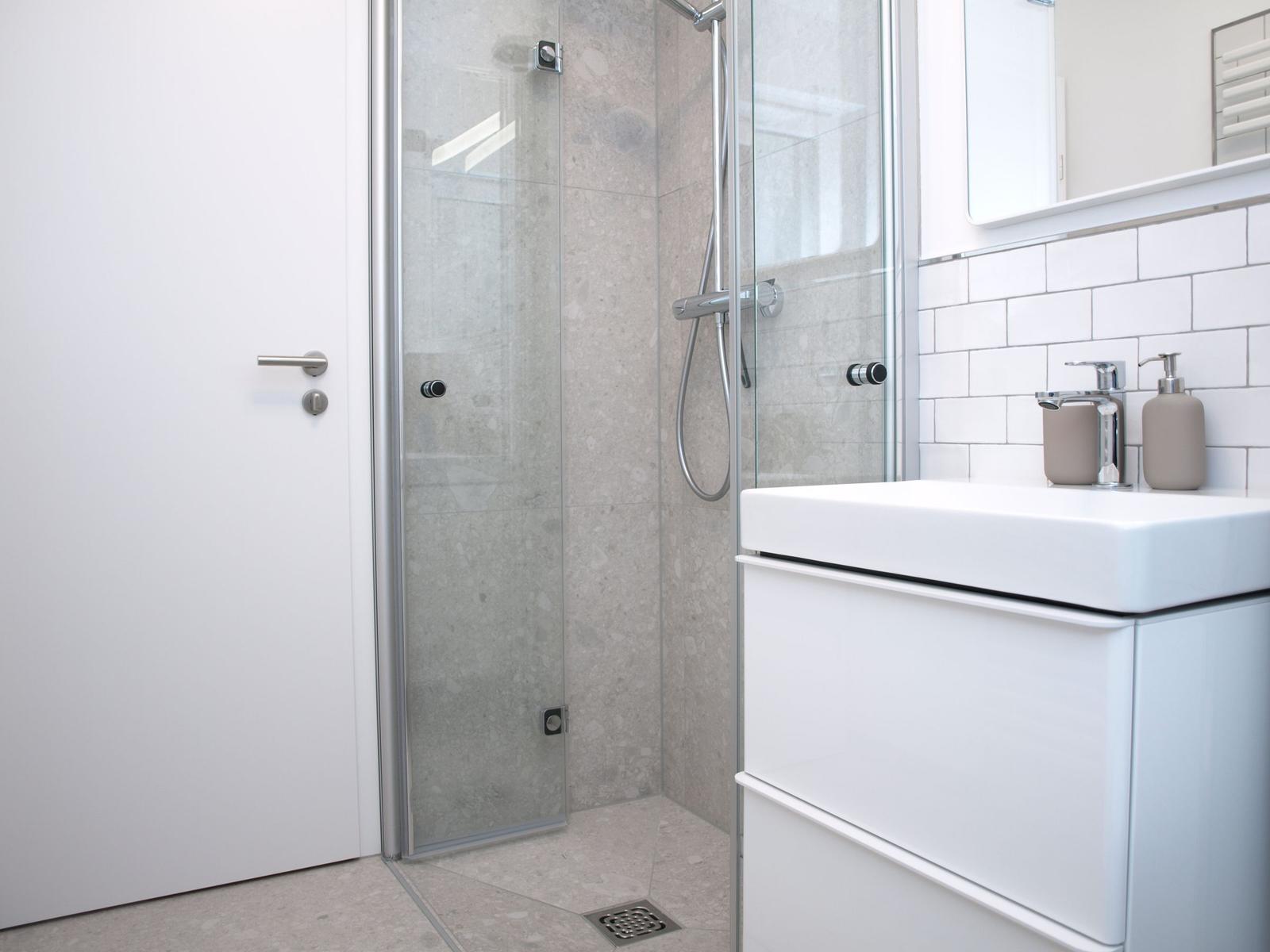 Badezimmer mit Dusche, Waschbecken und Spiegel