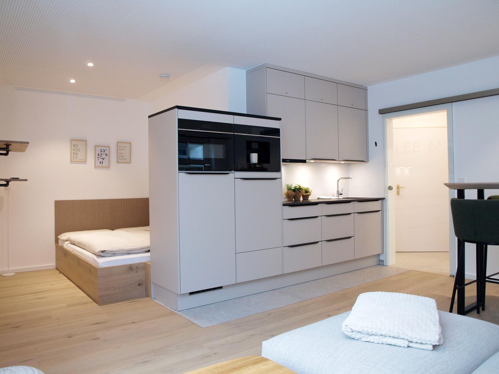 Moderne Küche mit integriertem Ofen und Schlafbereich mit Bett.