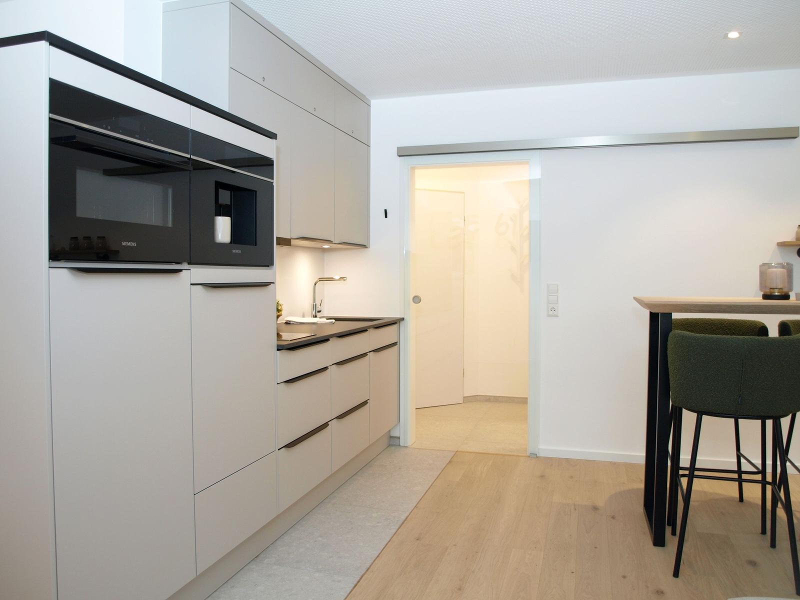 Moderne Küche mit integriertem Ofen und Arbeitsplatz mit Barhocker.