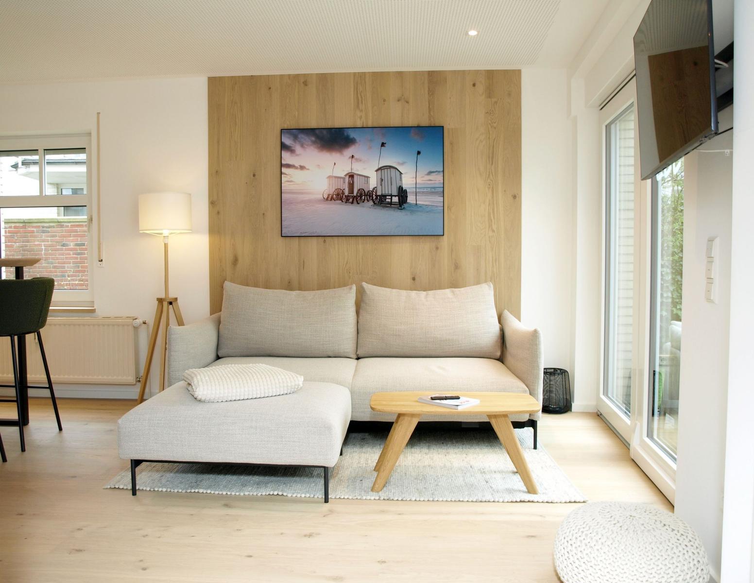 Ein Wohnzimmer mit Sofa, Couchtisch und Fernseher an Holzwand.