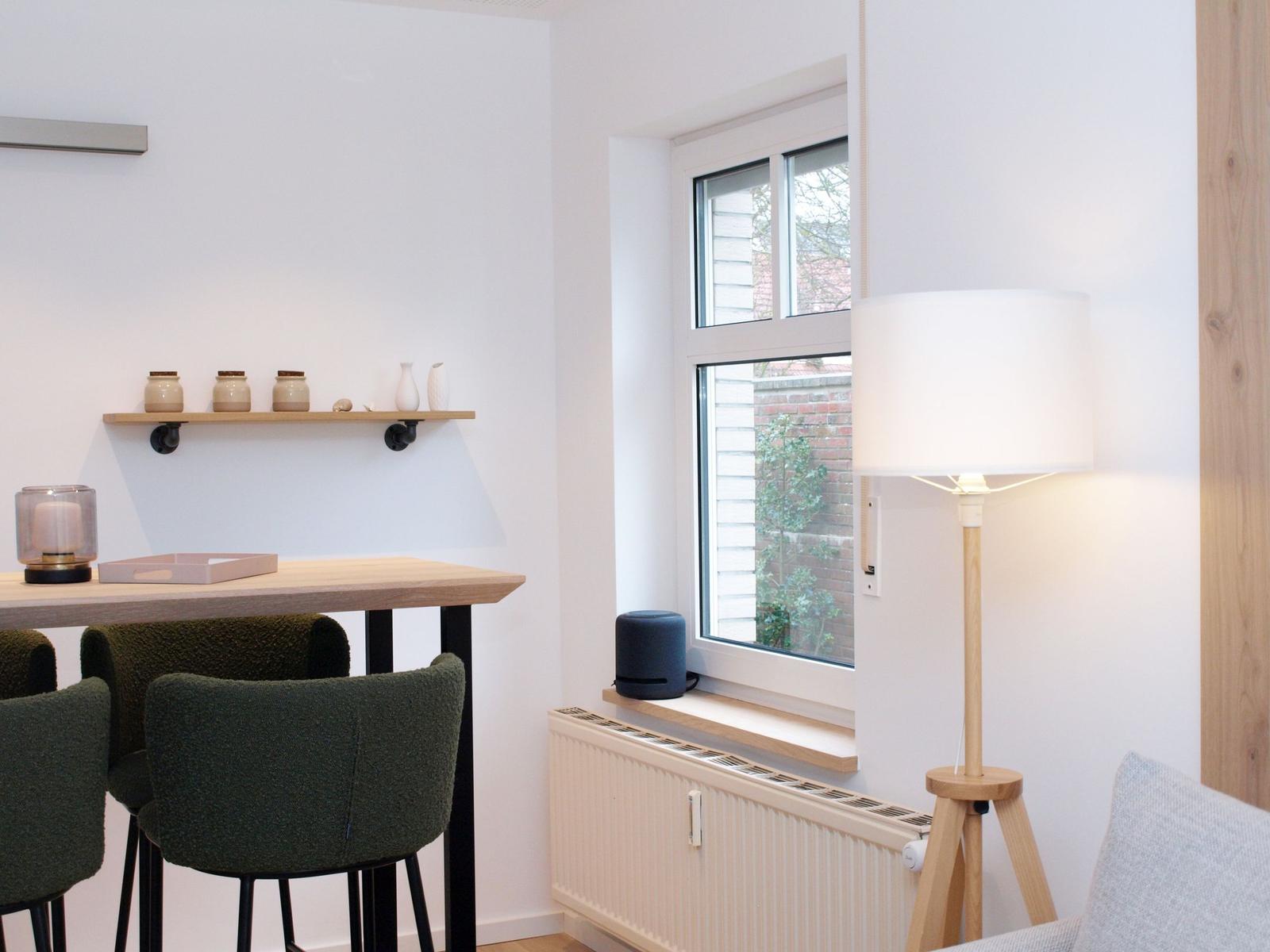Esstisch mit Stühlen, Fenster und Stehlampe im Raum.