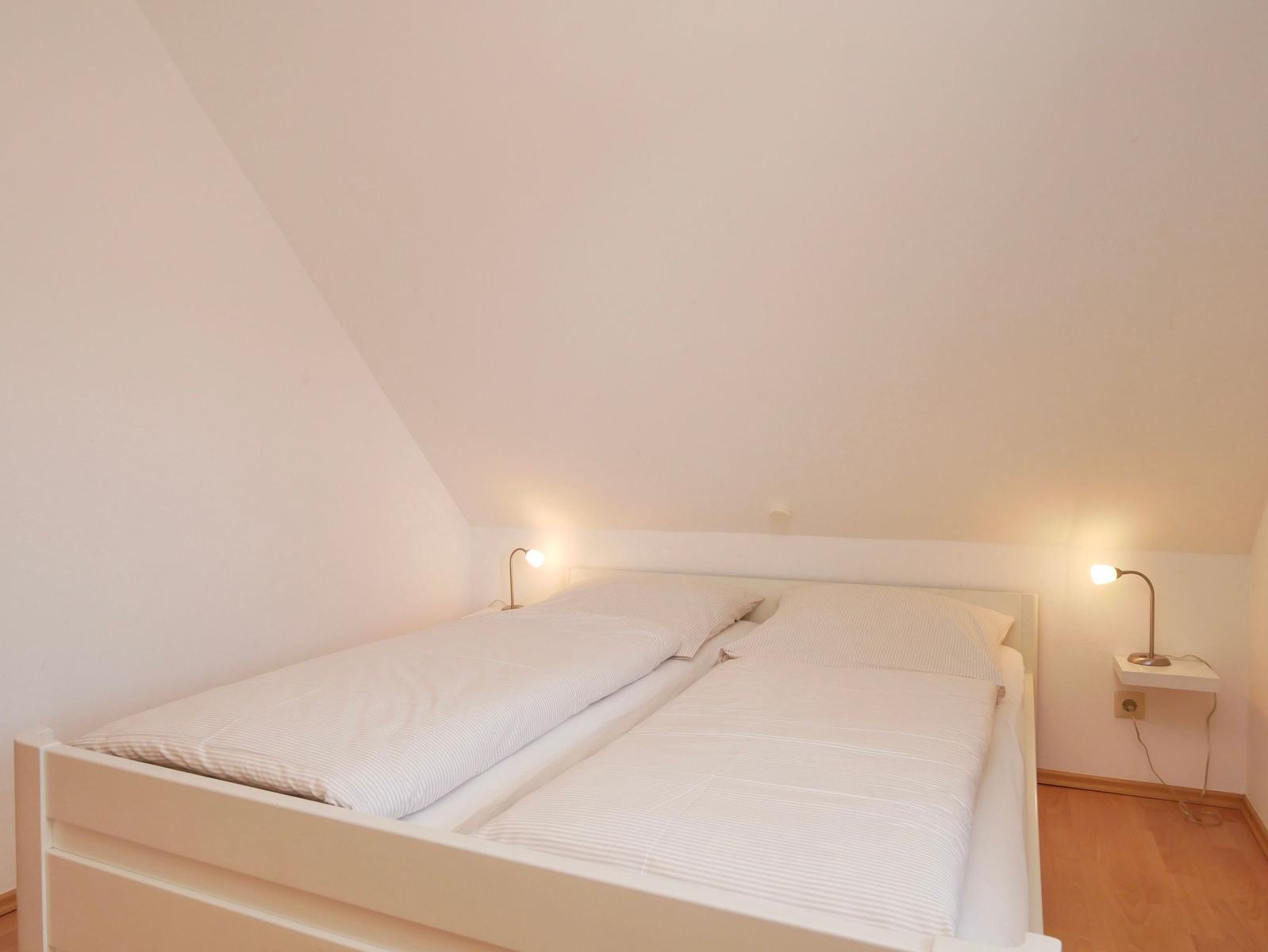 Schlafzimmer mit Doppelbett, zwei Nachttischen und Schrägdach.