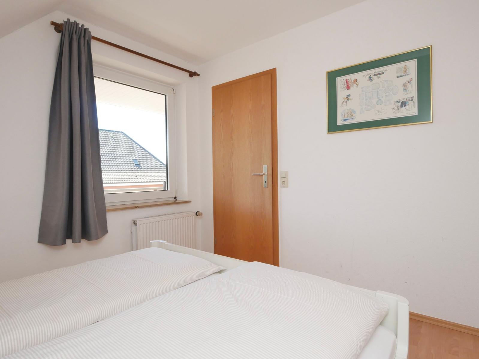 Ein Schlafzimmer mit Bett, Fenster und Tür.