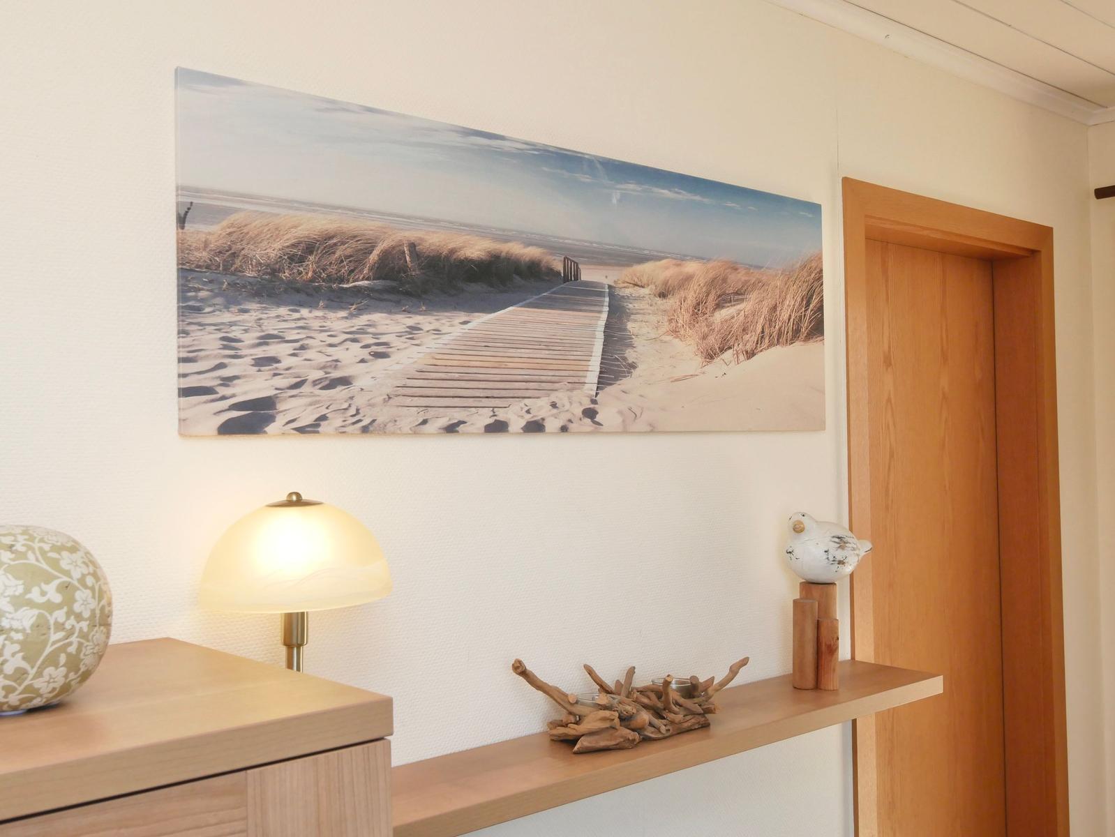 Wandbild mit Strandweg, Lampe und Dekoration auf Holzregal