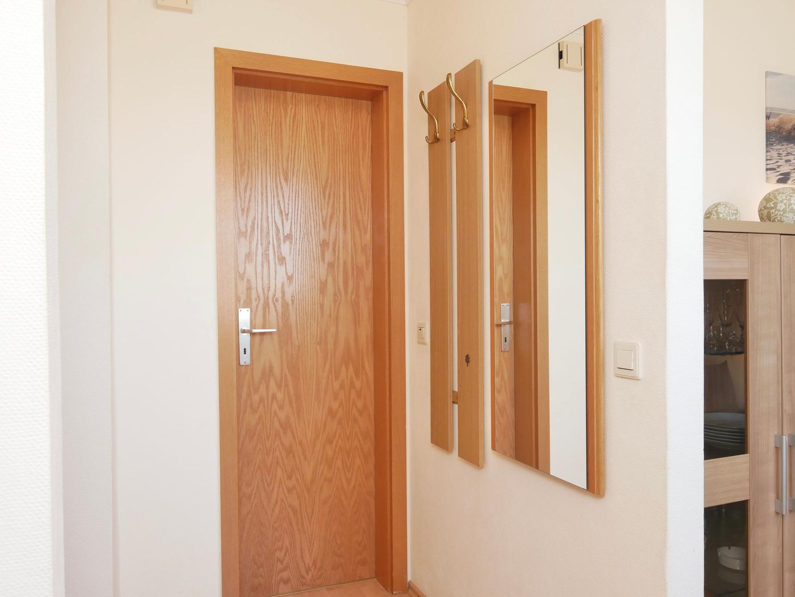 Hausflur mit Holztür, Spiegel und Garderobe