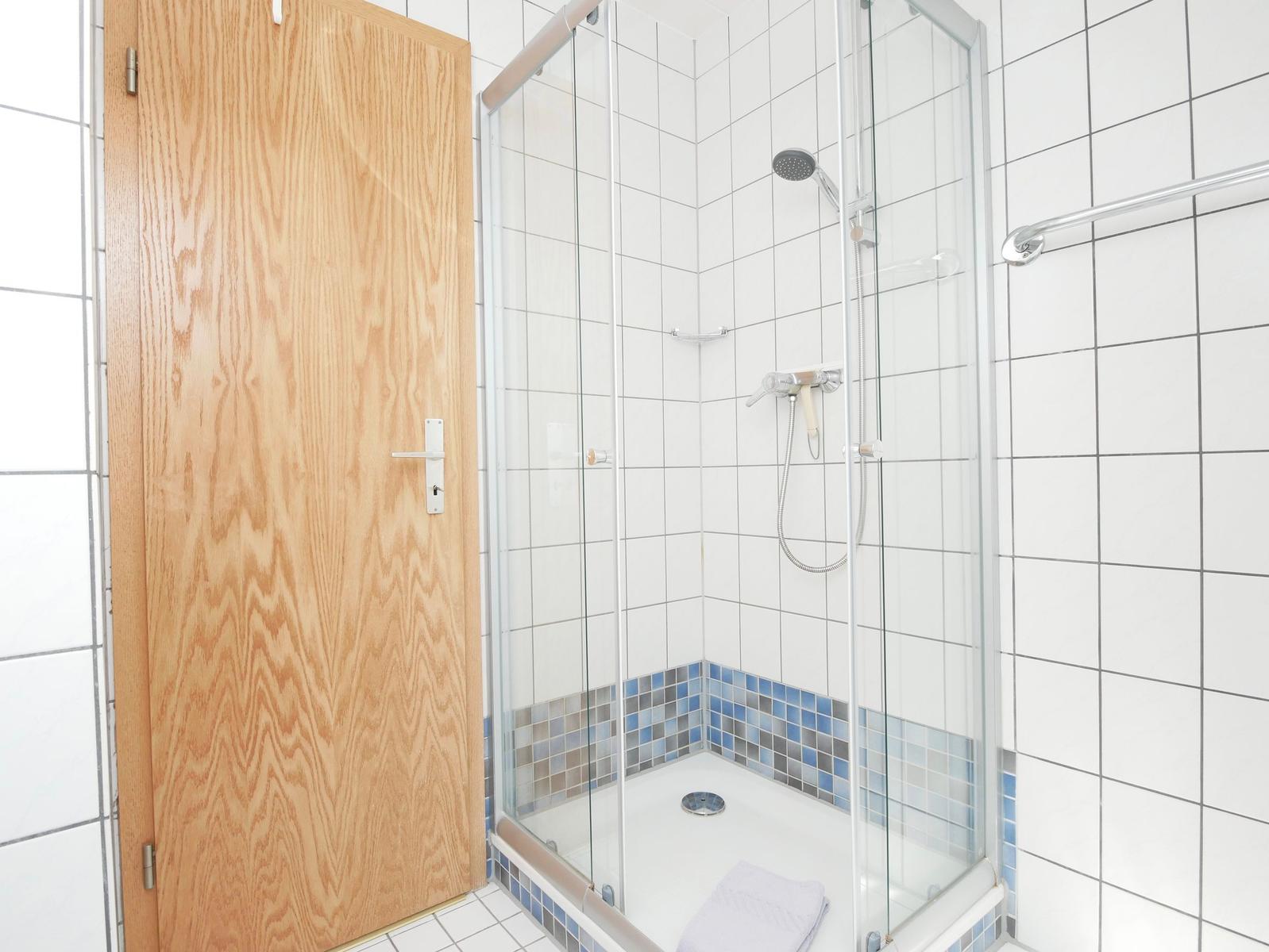Duschkabine mit Glaswand und blauen Fliesen an der Wand