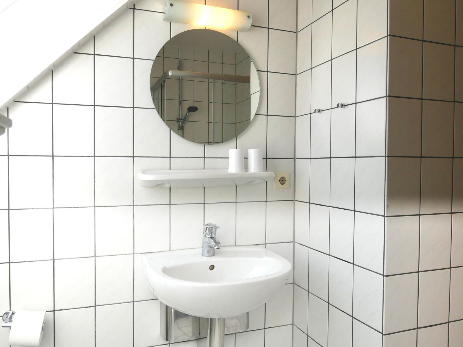 Badezimmer mit Waschbecken, Spiegel und Dusche.