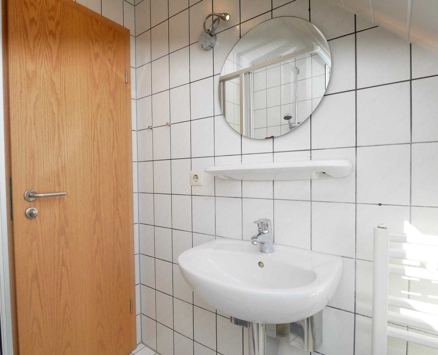 Badezimmer mit Waschbecken, Spiegel und Dusche.
