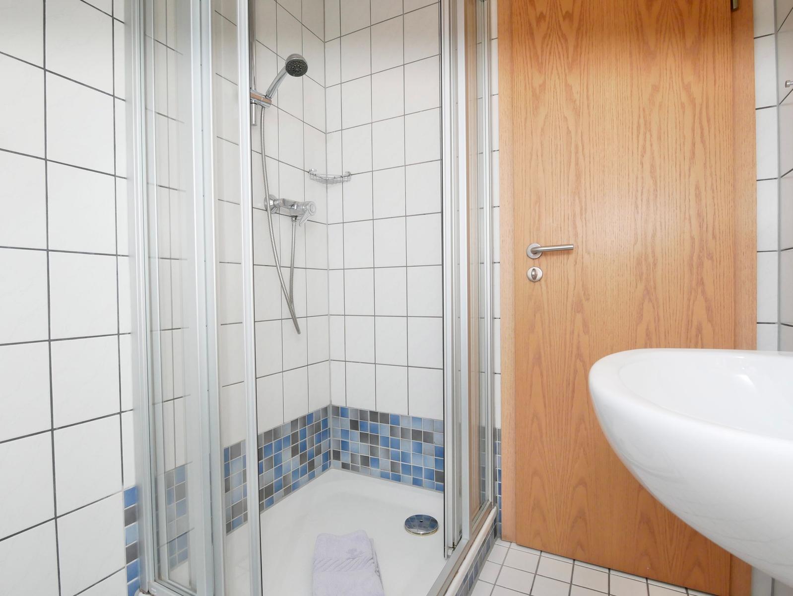 Dusche mit Glaswand, blauen Fliesen und Waschbecken