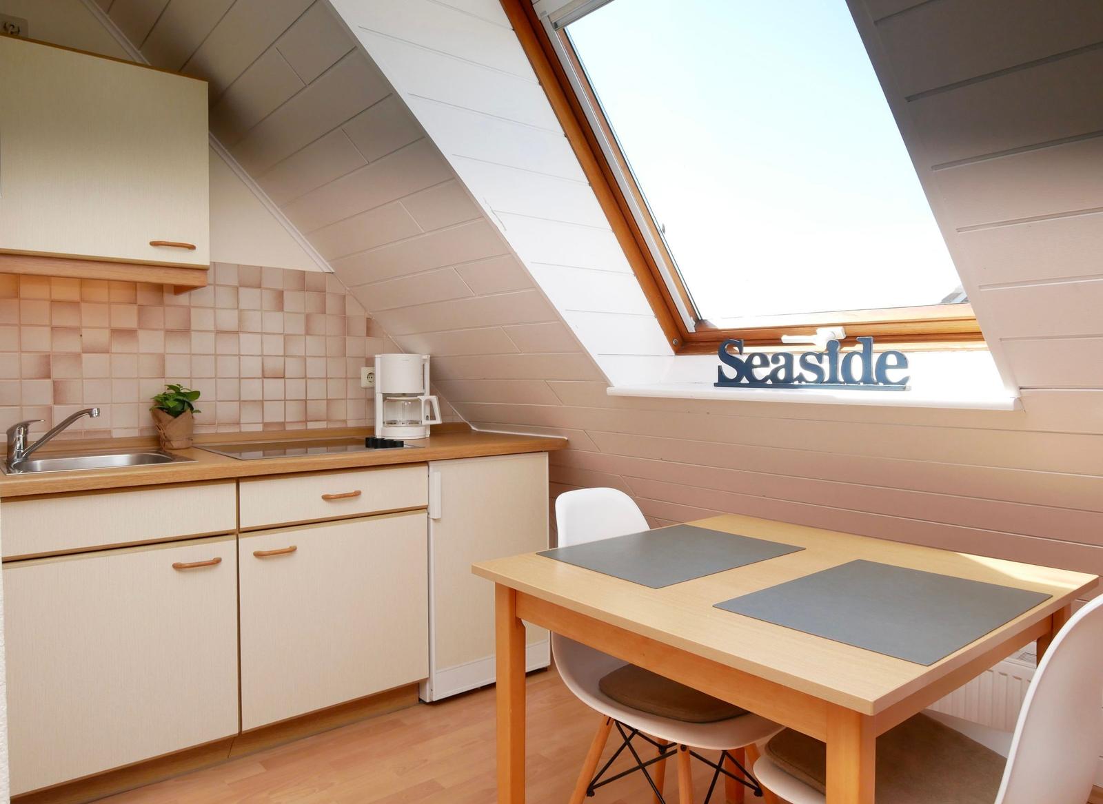 Küche mit Esstisch unter Dachschrägen und Dachfenster mit Schild Seaside.