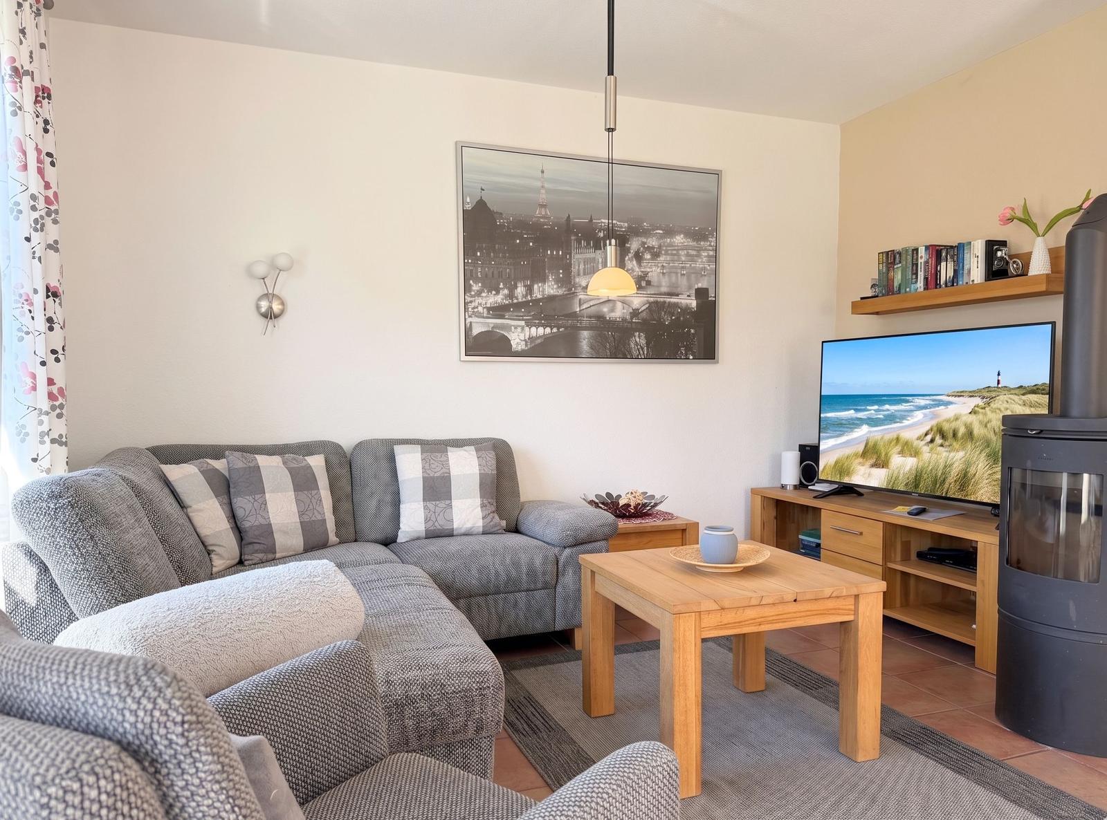 Wohnzimmer mit Sofa, Couchtisch und Fernseher. Wandbild und Kamin sichtbar.