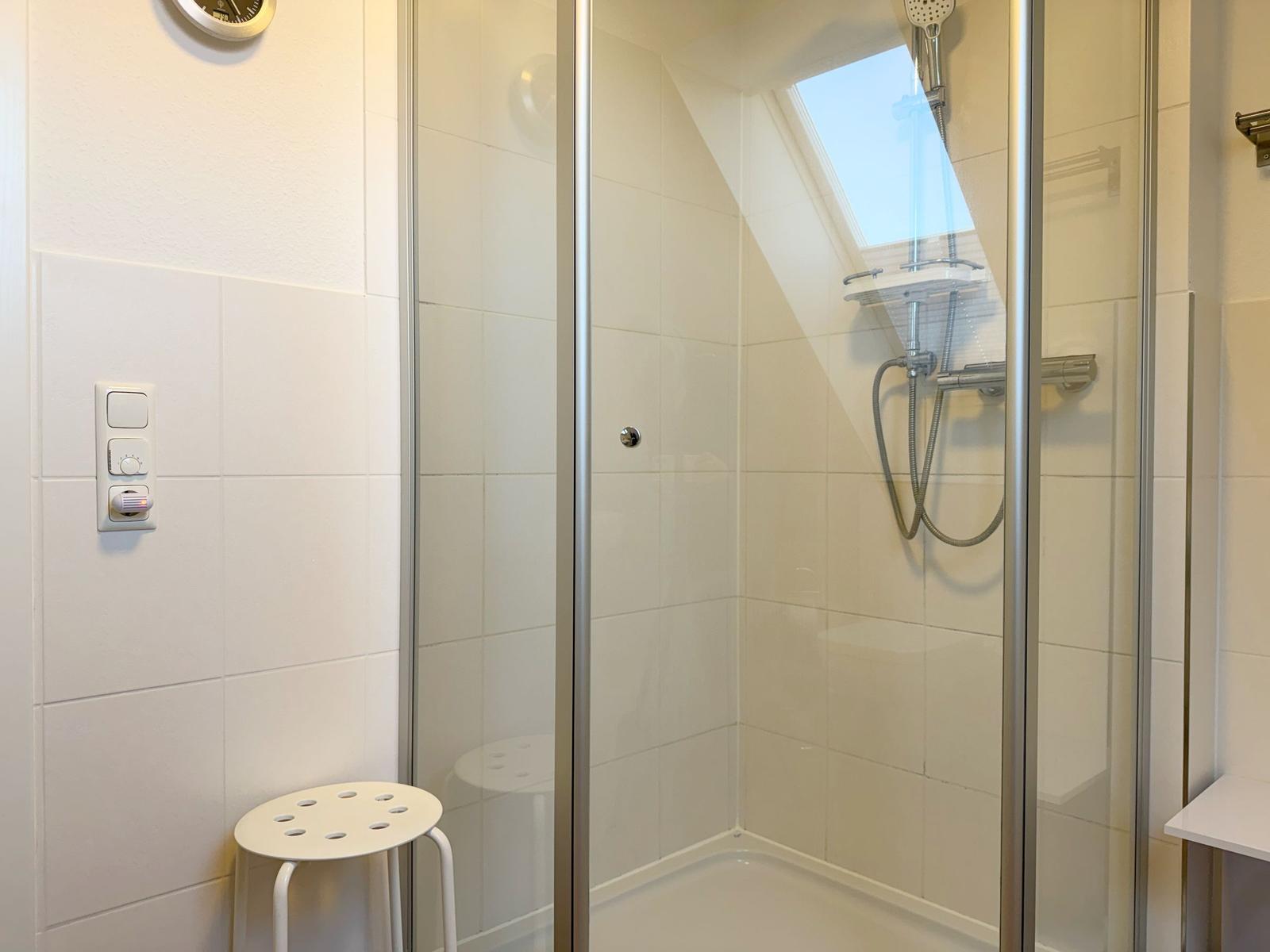 Dusche mit Glaswand, Duschbrause und Duschsitz