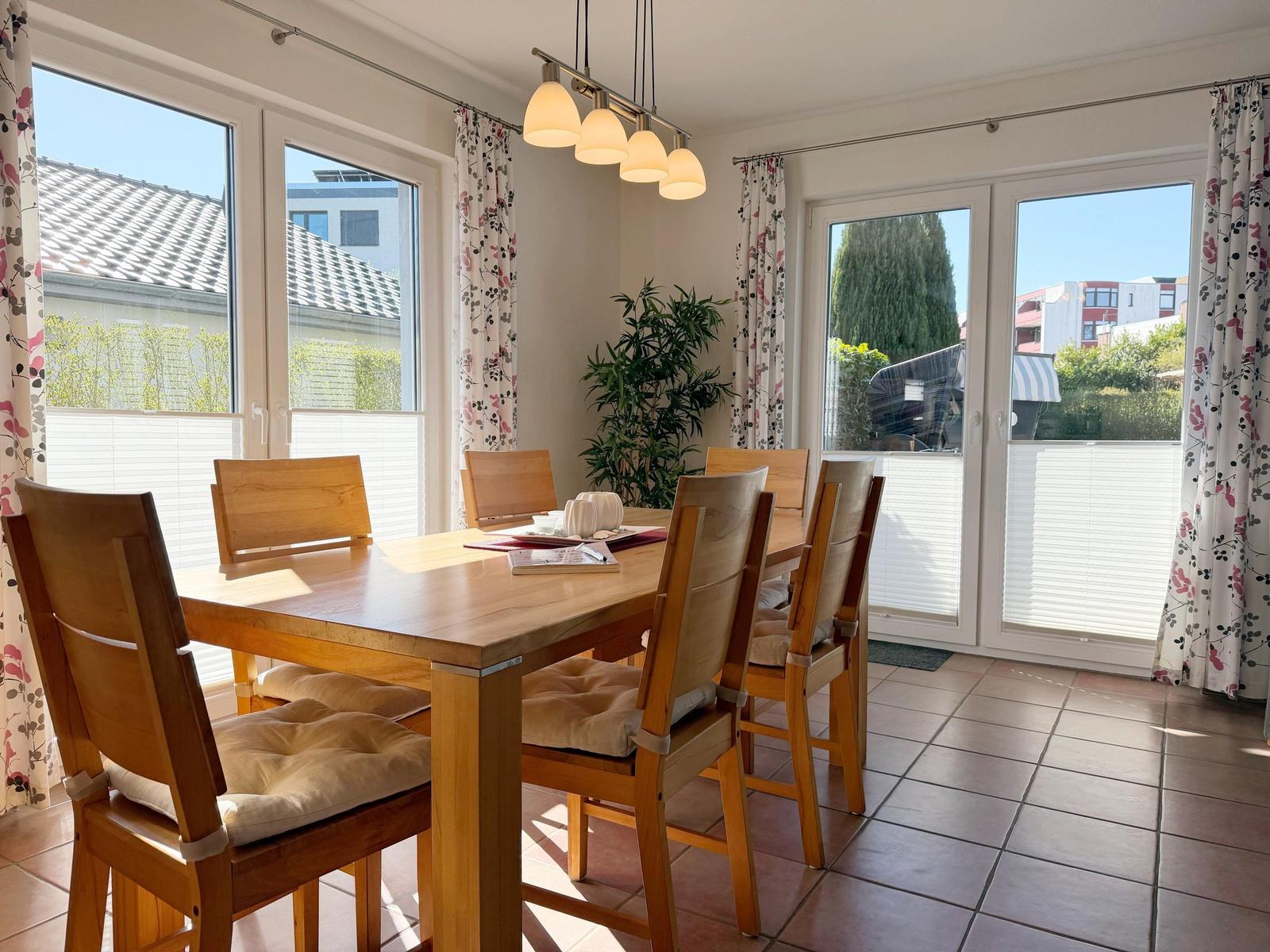 Esszimmer mit Holztisch, Stühlen und Blick auf Balkon.