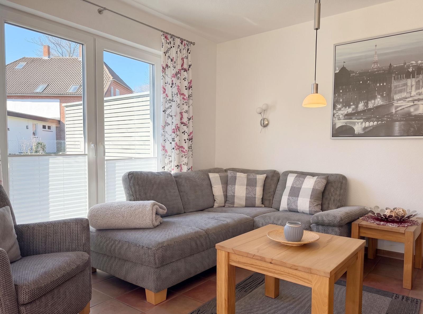 Wohnzimmer mit Sofa, Tisch und Fenster zur Terrasse.