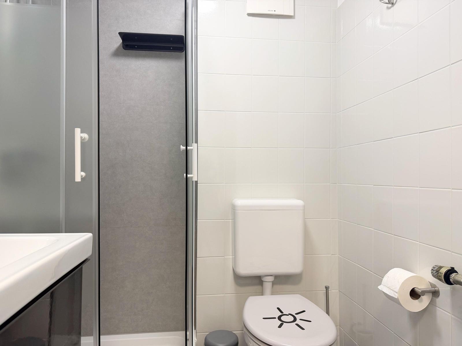Badezimmer mit Dusche, Toilette und Waschbecken.