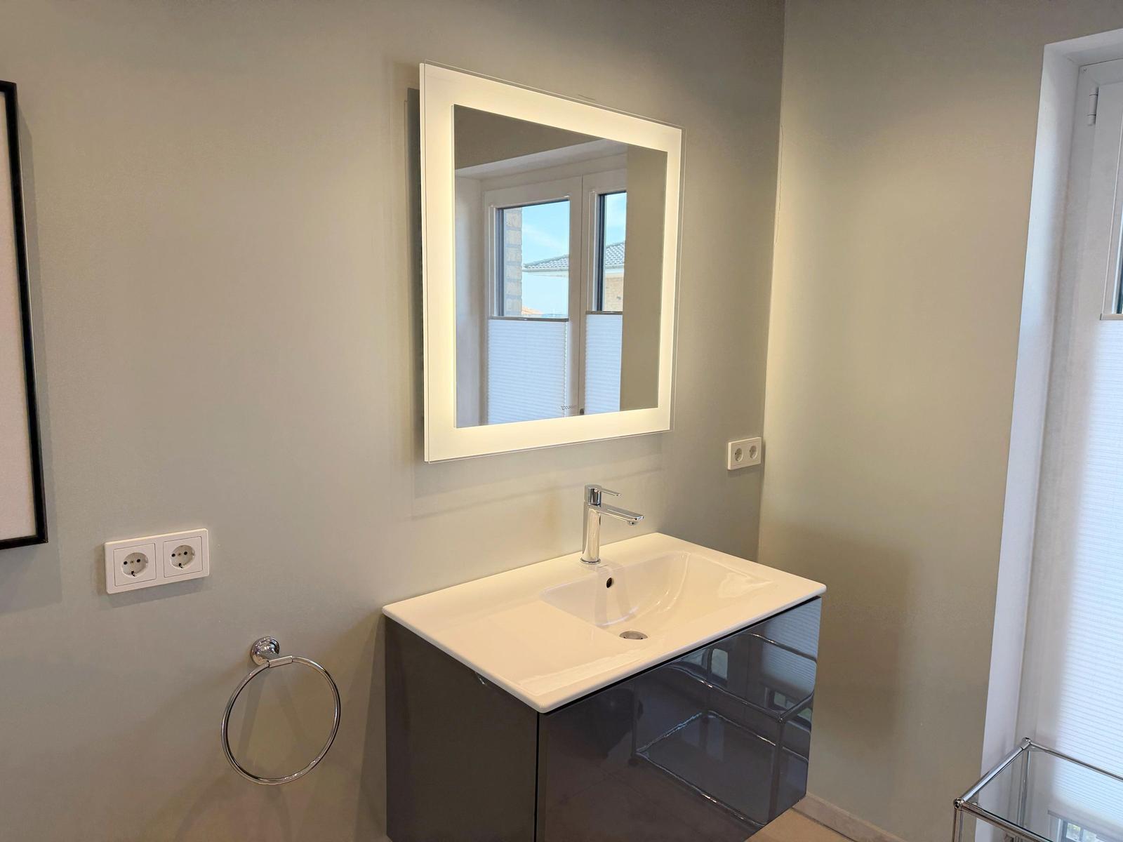 Badezimmer mit Waschtisch, Spiegel und Fenster