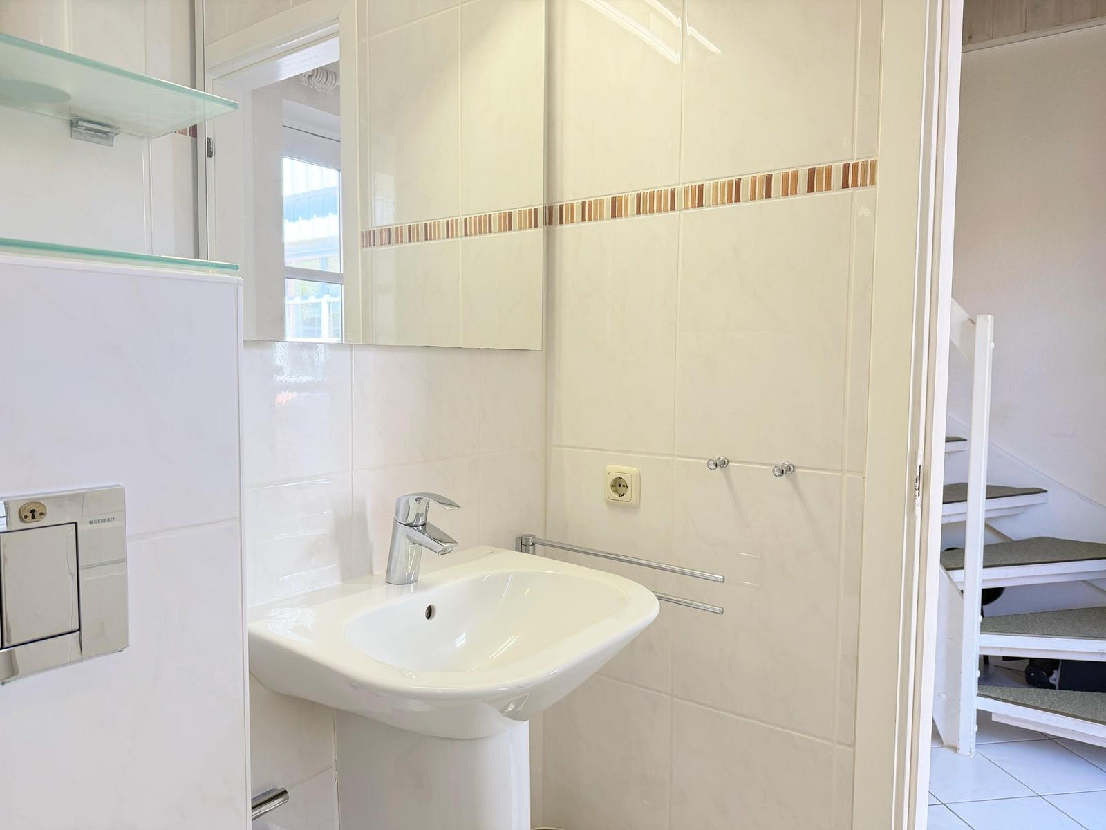 Badezimmer mit Waschbecken, Spiegel und Badewannenbereich